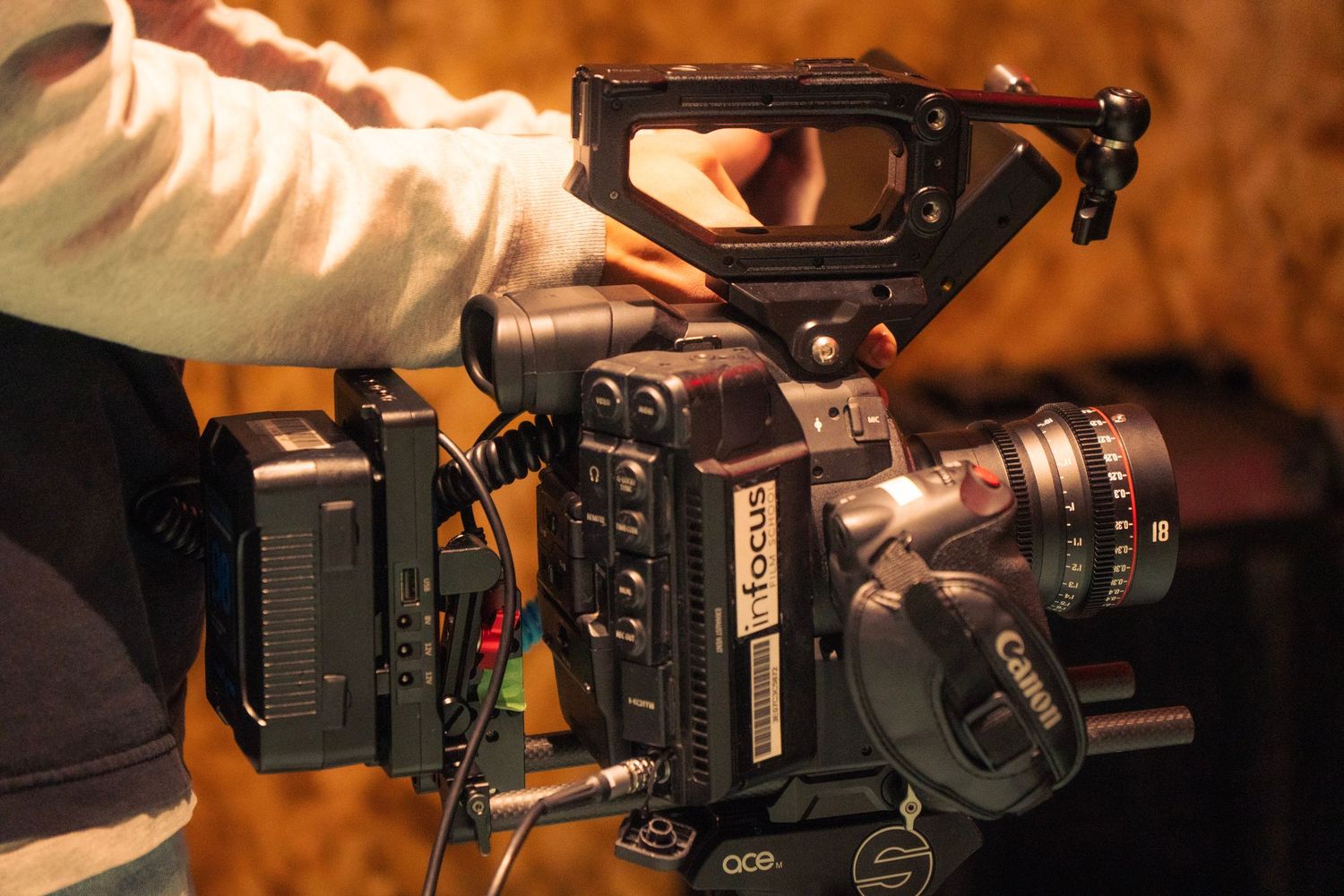 Cinematographer holding a professional Canon cinema camera on a film production set.