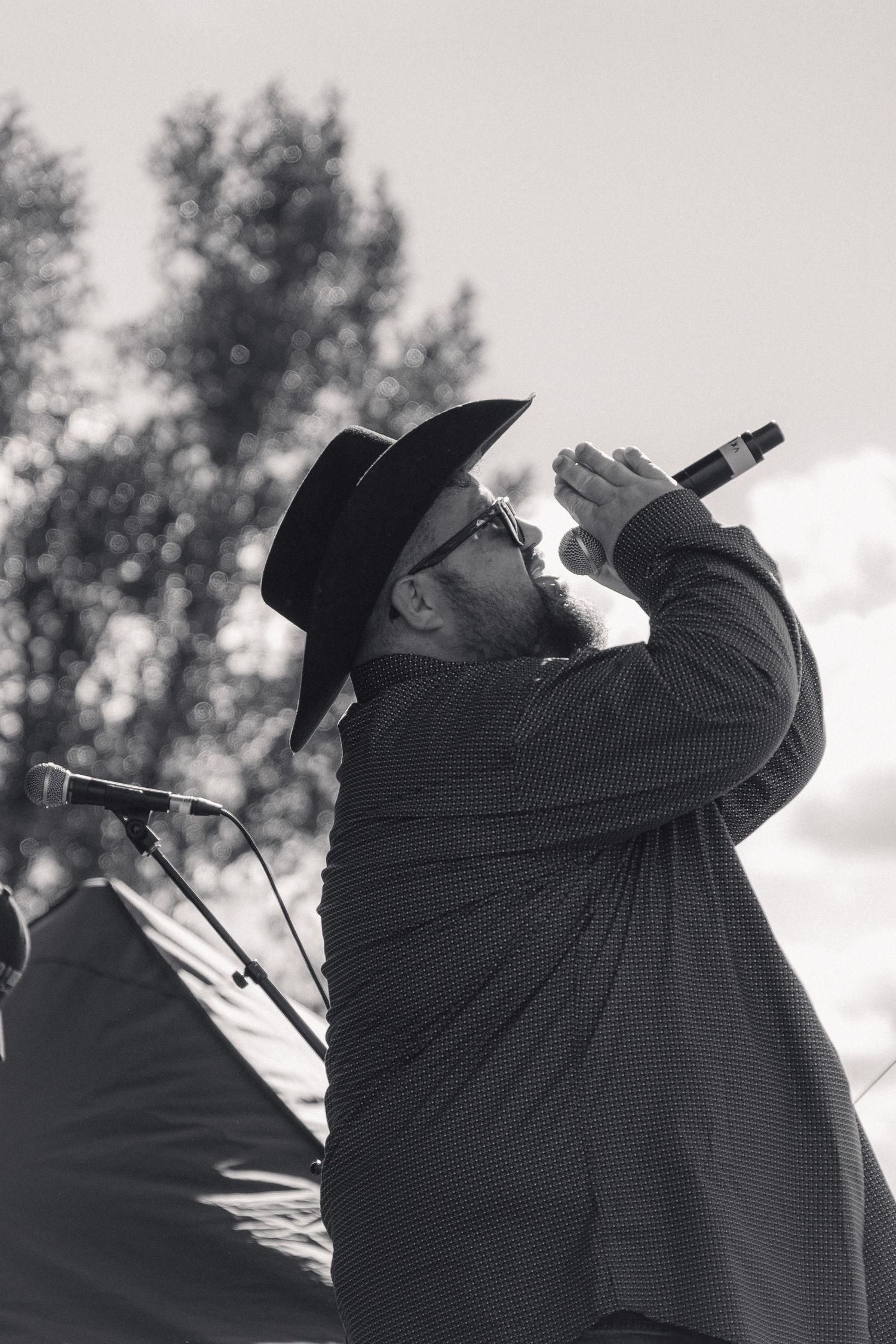 Black and white photo of bearded male singer in cowboy hat performing passionately with microphone.