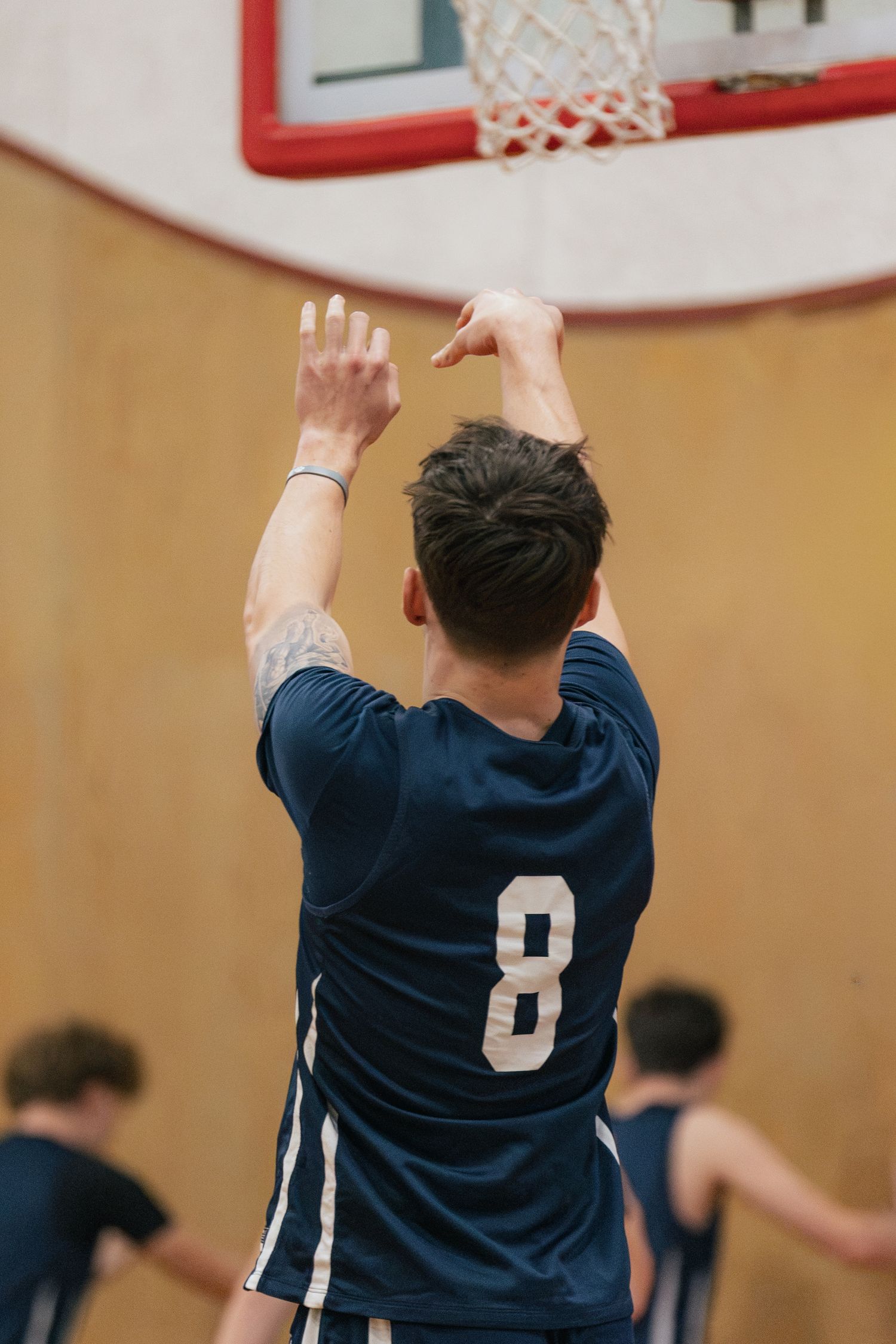 A basketball player wearing number 8 shoots toward the hoop during an indoor gymnasium game.
