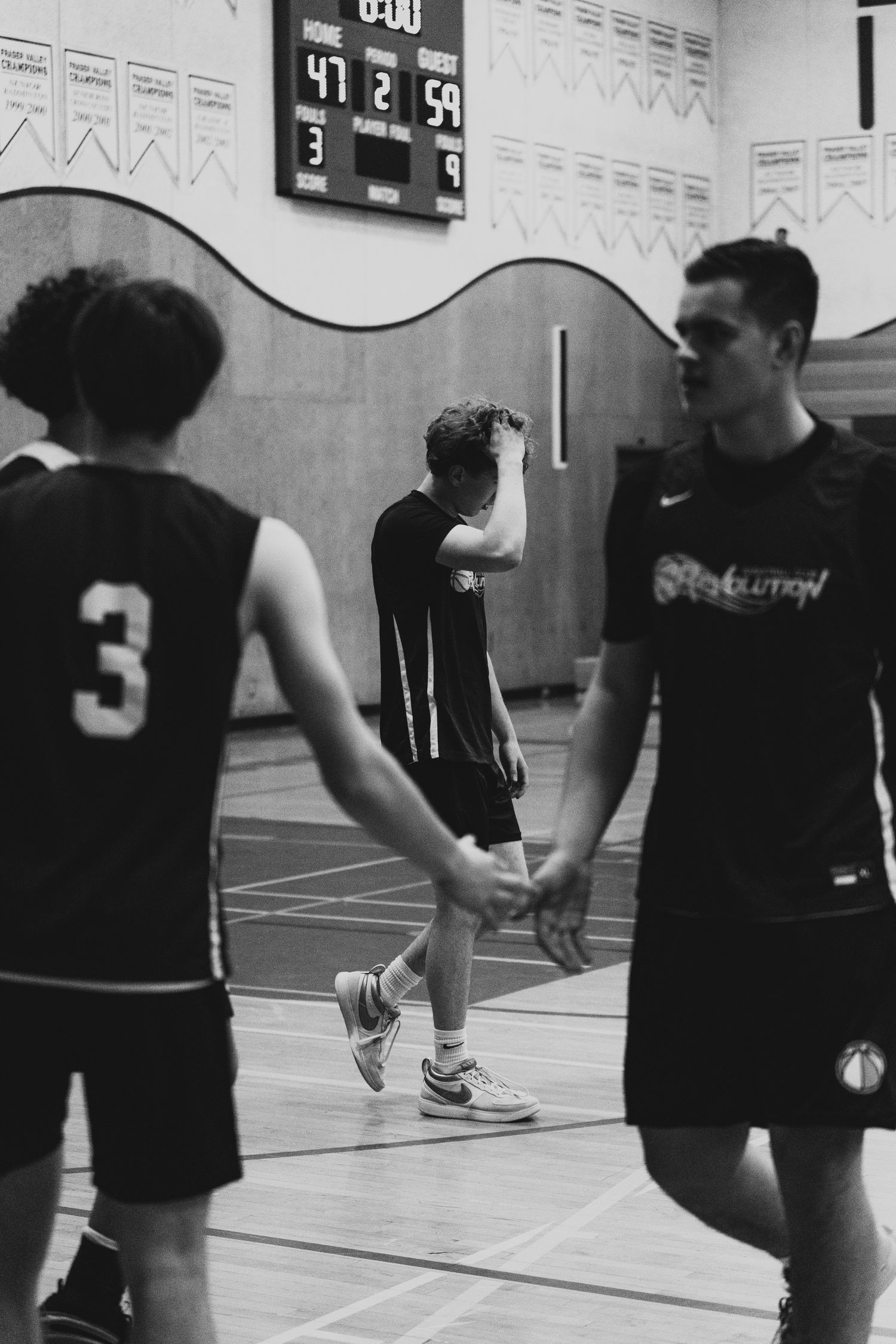 Black and white photo of basketball players shaking hands after a game, scoreboard showing 47-59.
