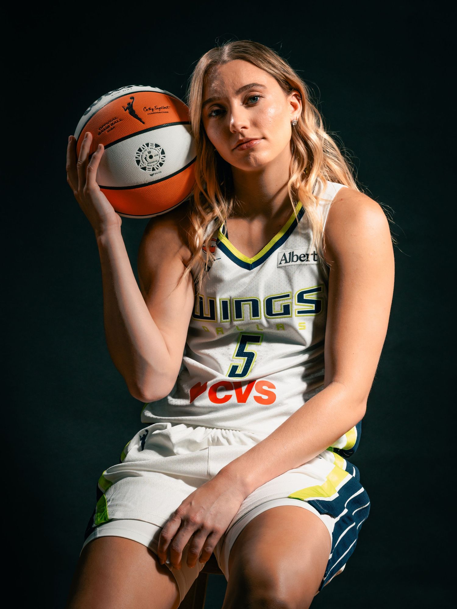 Paige Bueckers, basketball player wearing a white jersey number 5 looking straight with a black background
