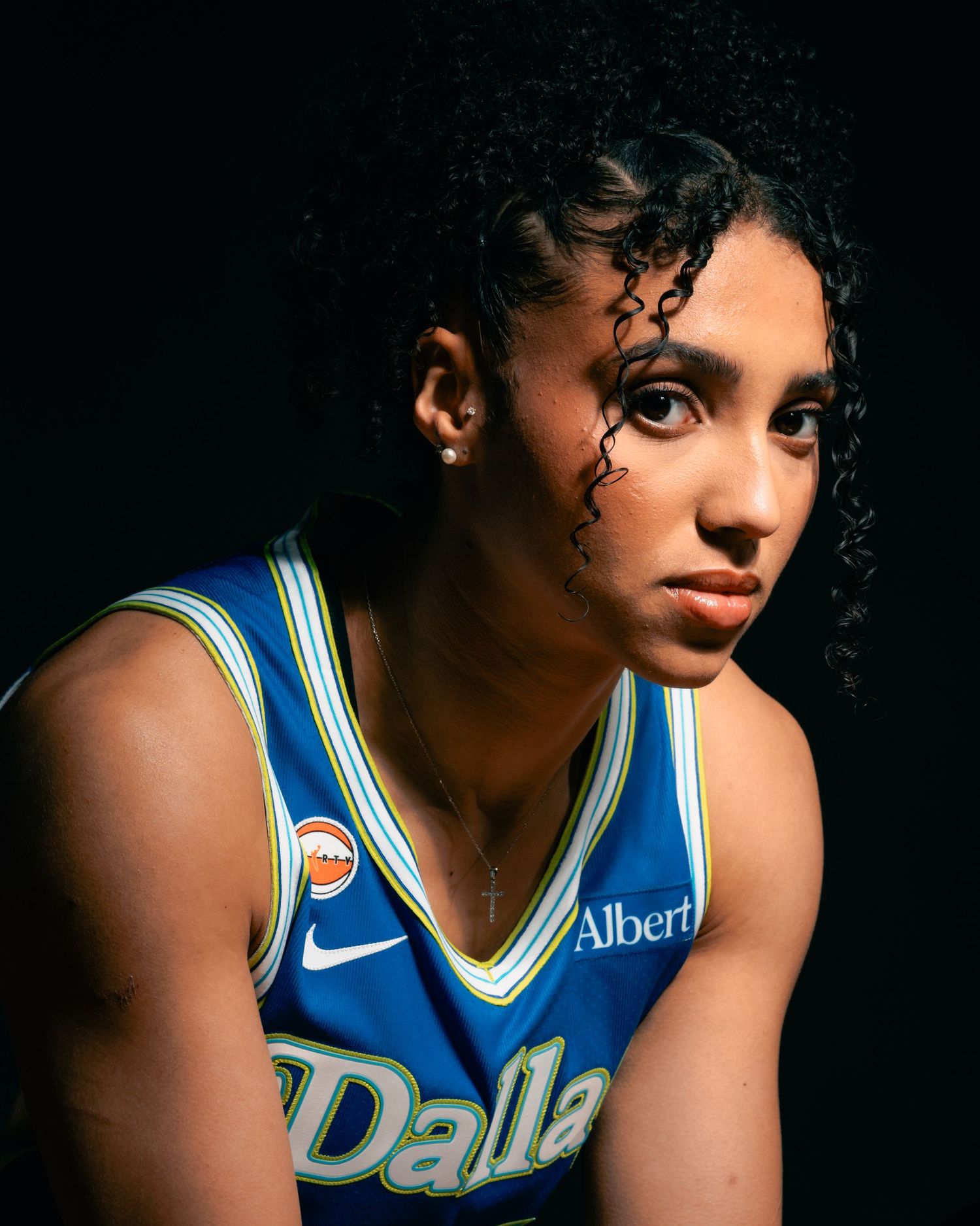 Azzi Fudd, basketball player wearing a blue jersey  looking straight with a black background