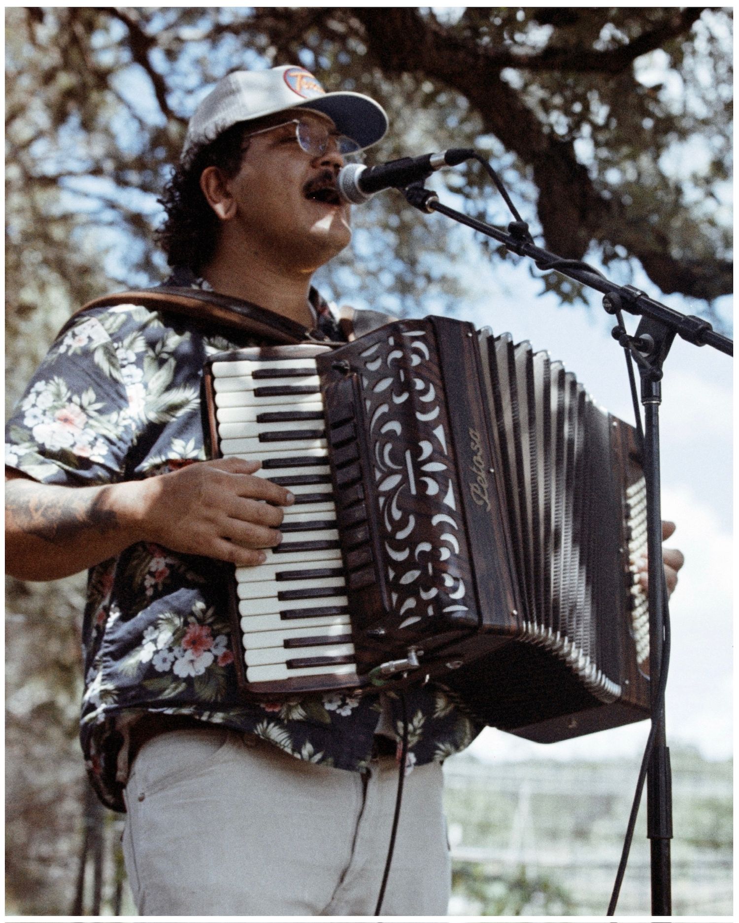 Musician playing an accordion outdoors against a bright background with multiple views of the performance.