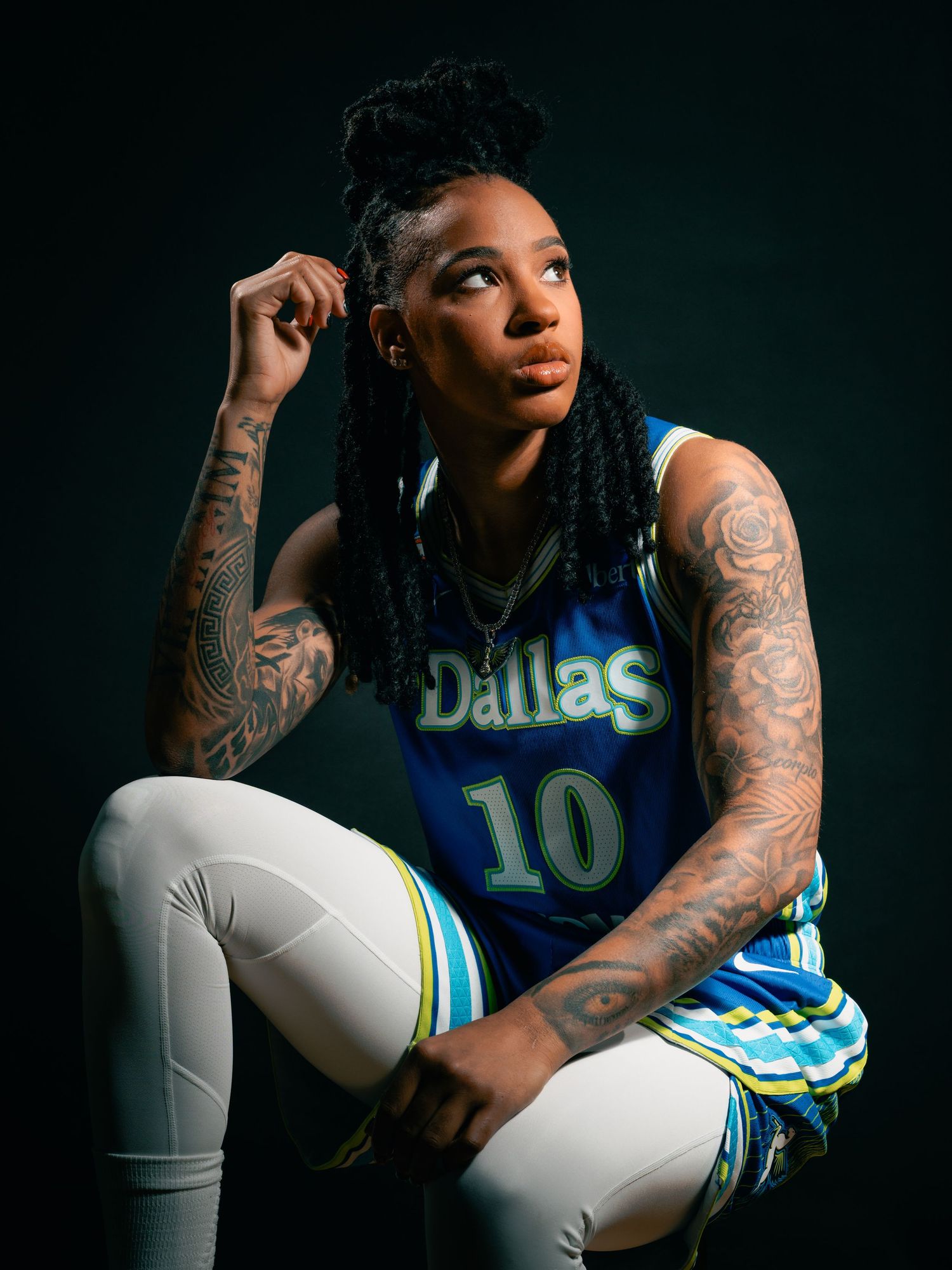 Aziaha James, basketball player wearing a blue jersey number 10 looking up to the right with a black background