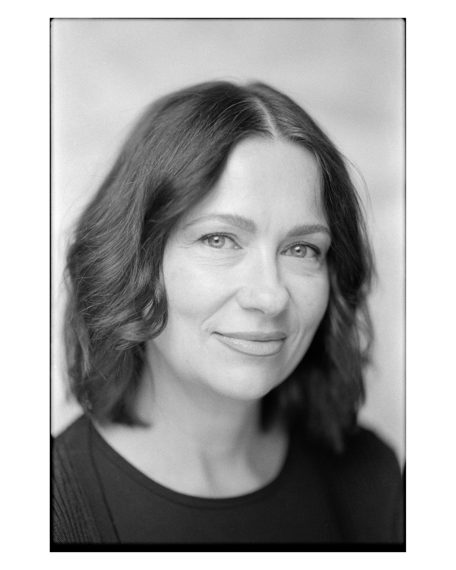 Professional black and white headshot of woman with wavy dark hair and gentle smile.