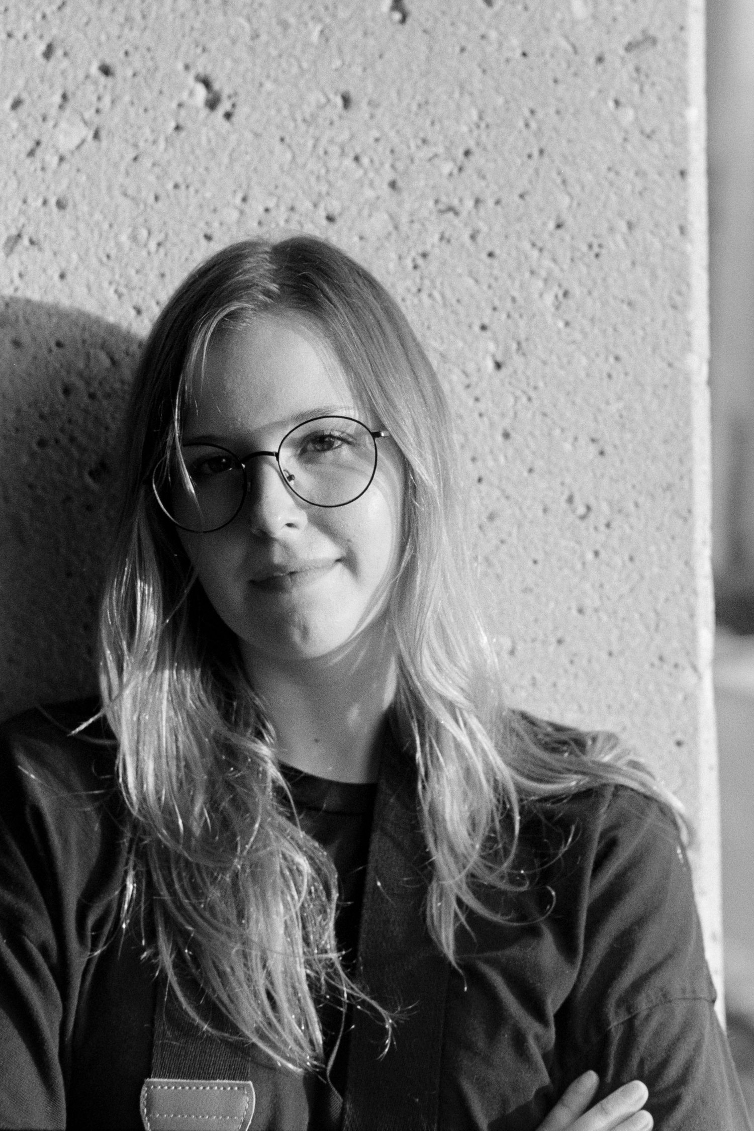 Black and white portraits of a person with glasses against a textured wall.