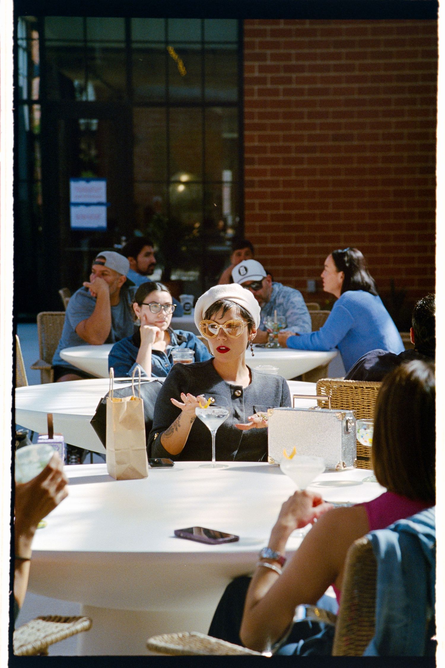 People sitting at white tables in a cafeteria with brick walls.