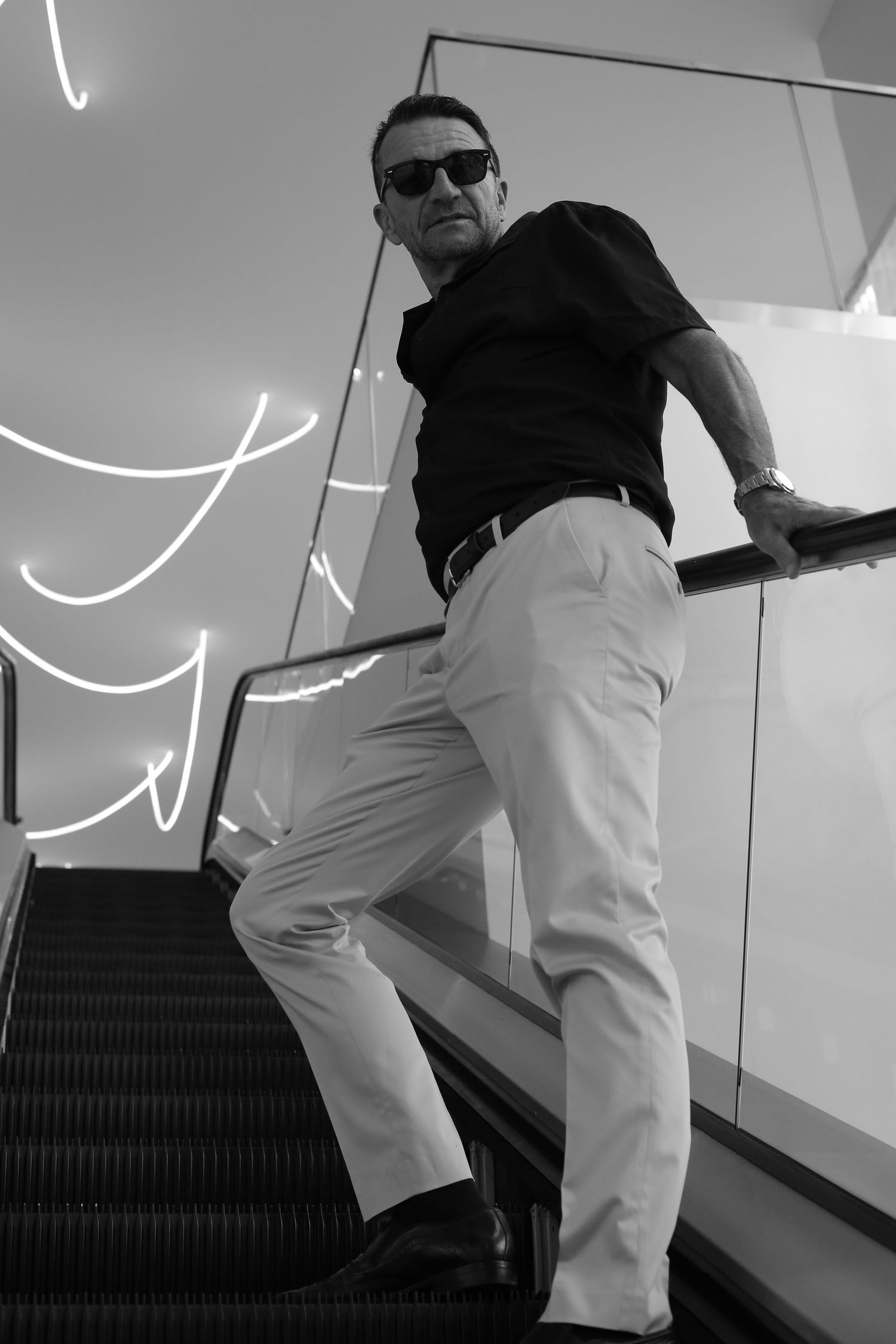 Black and white series showing person walking up escalator in artistic composition.