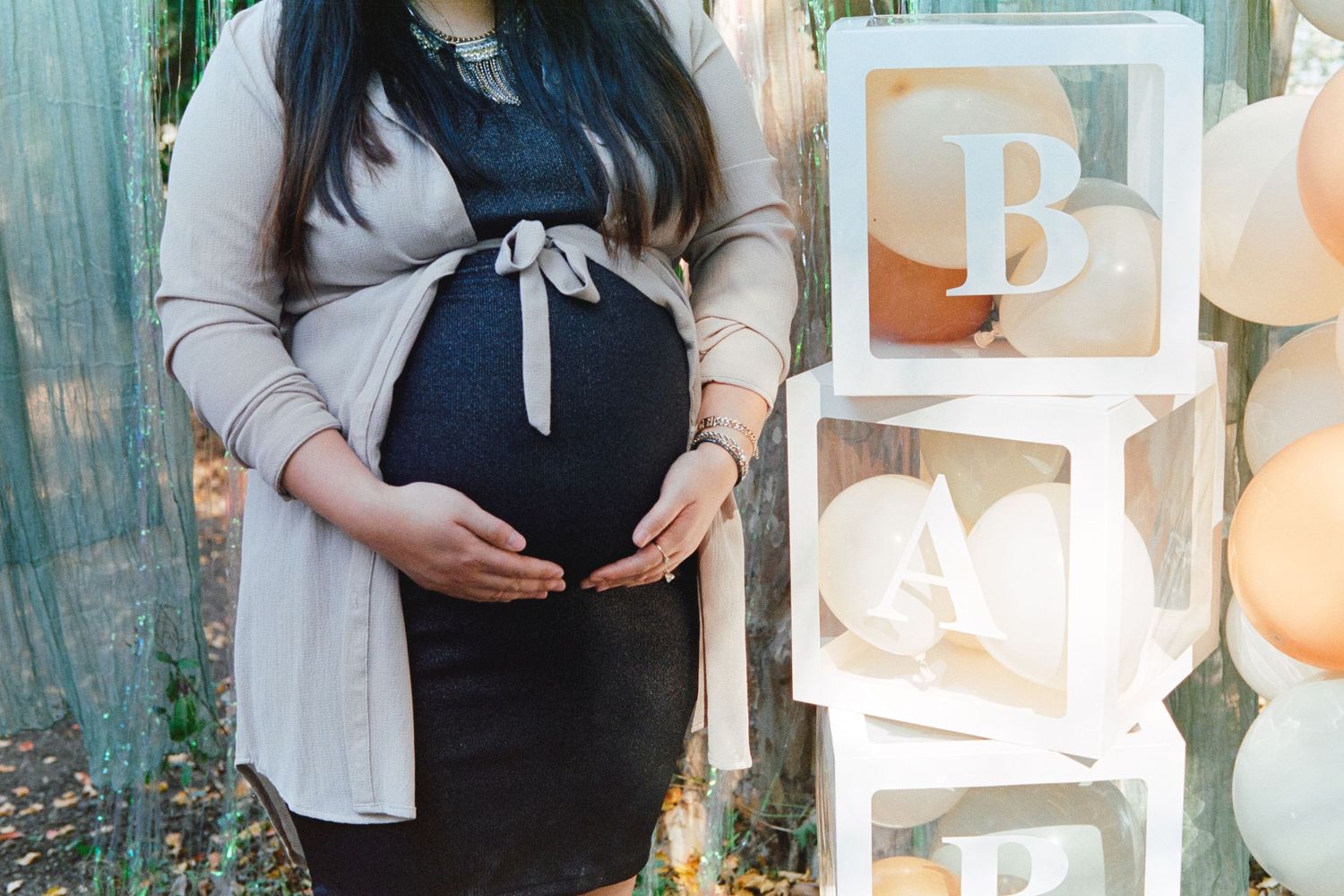 A maternity photo session in a garden setting with soft natural lighting and flowing fabric details.