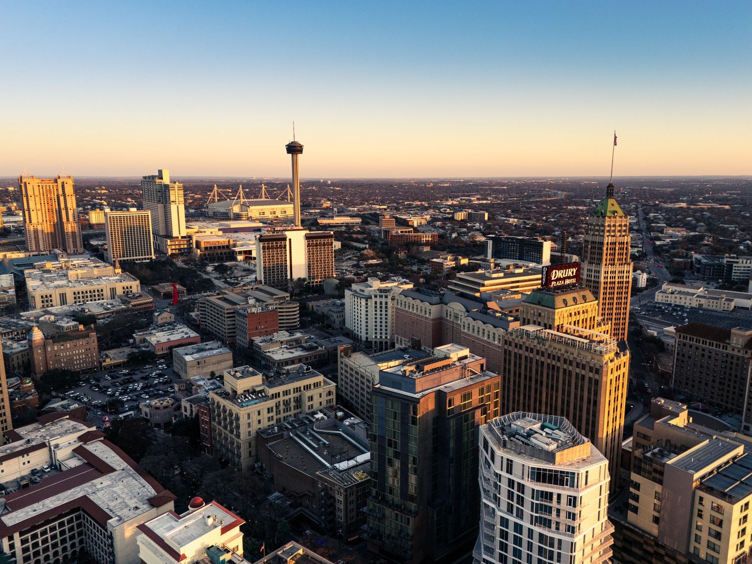 Aerial panorama of San Antonio skyline during sunset showing urban architecture.