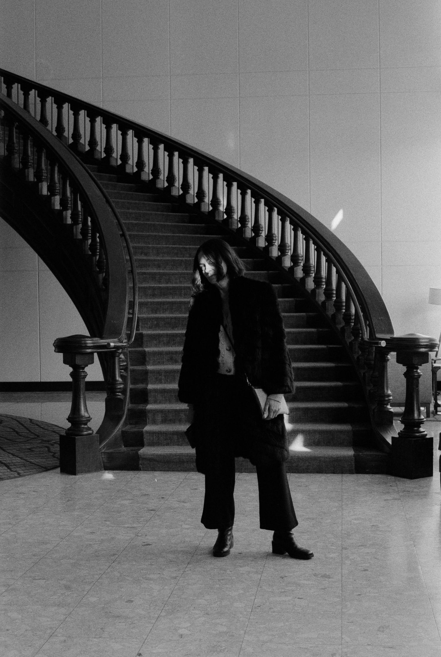 Dramatic black and white sequence showing figures descending a grand curved staircase.