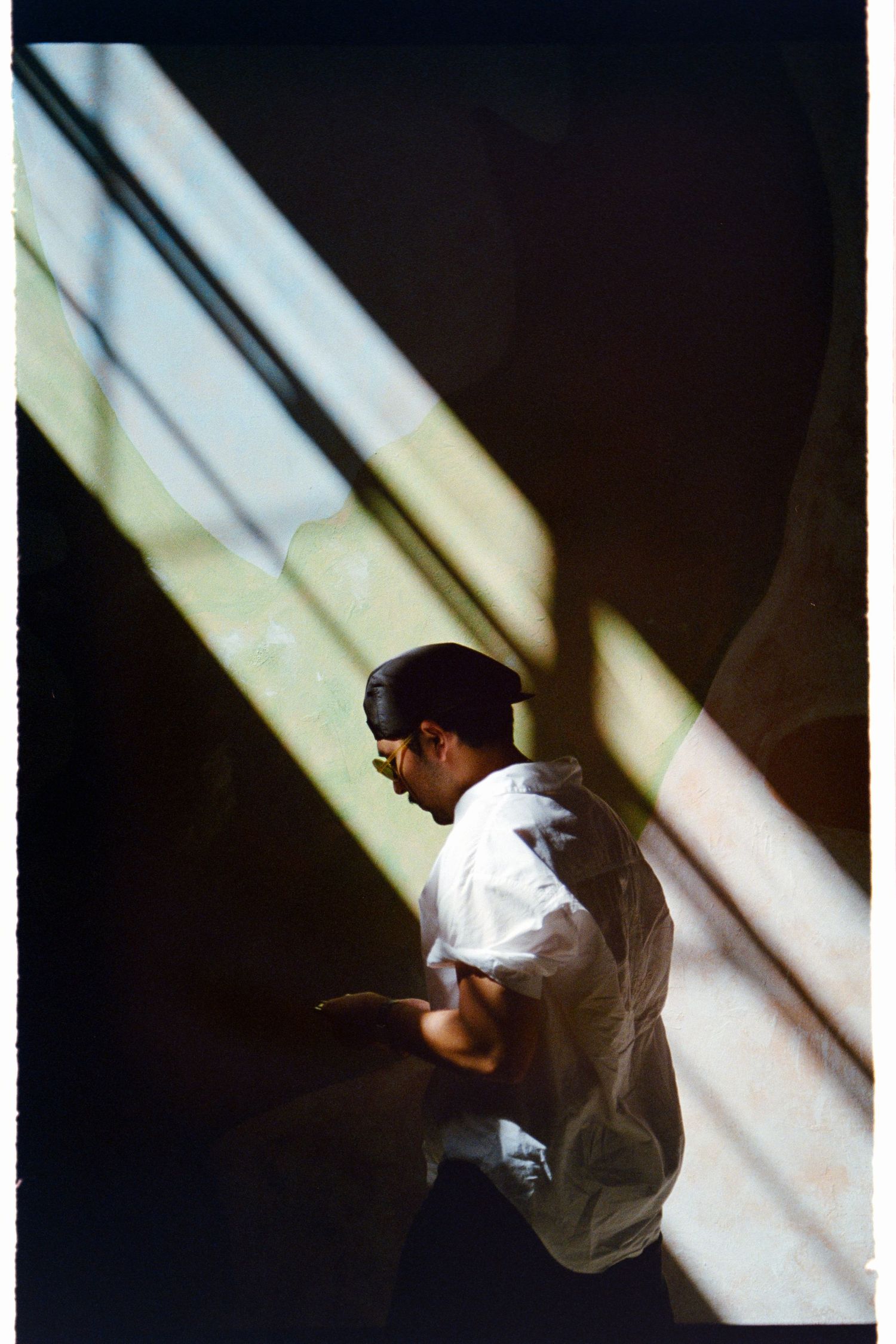 Dramatic silhouette of person in white shirt against diagonal light beams.