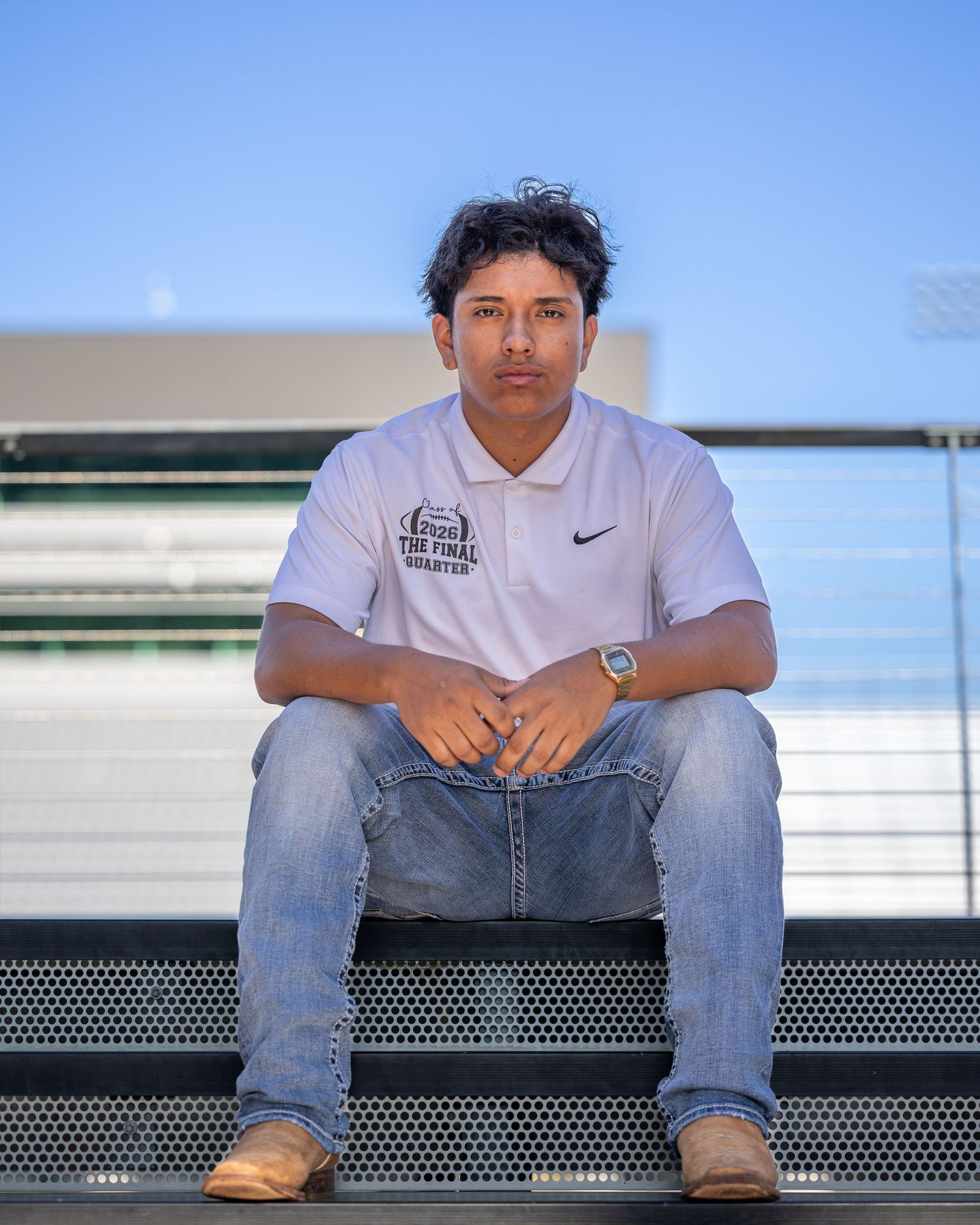 Individual portrait of a young male athlete sitting on stadium bleachers during the day