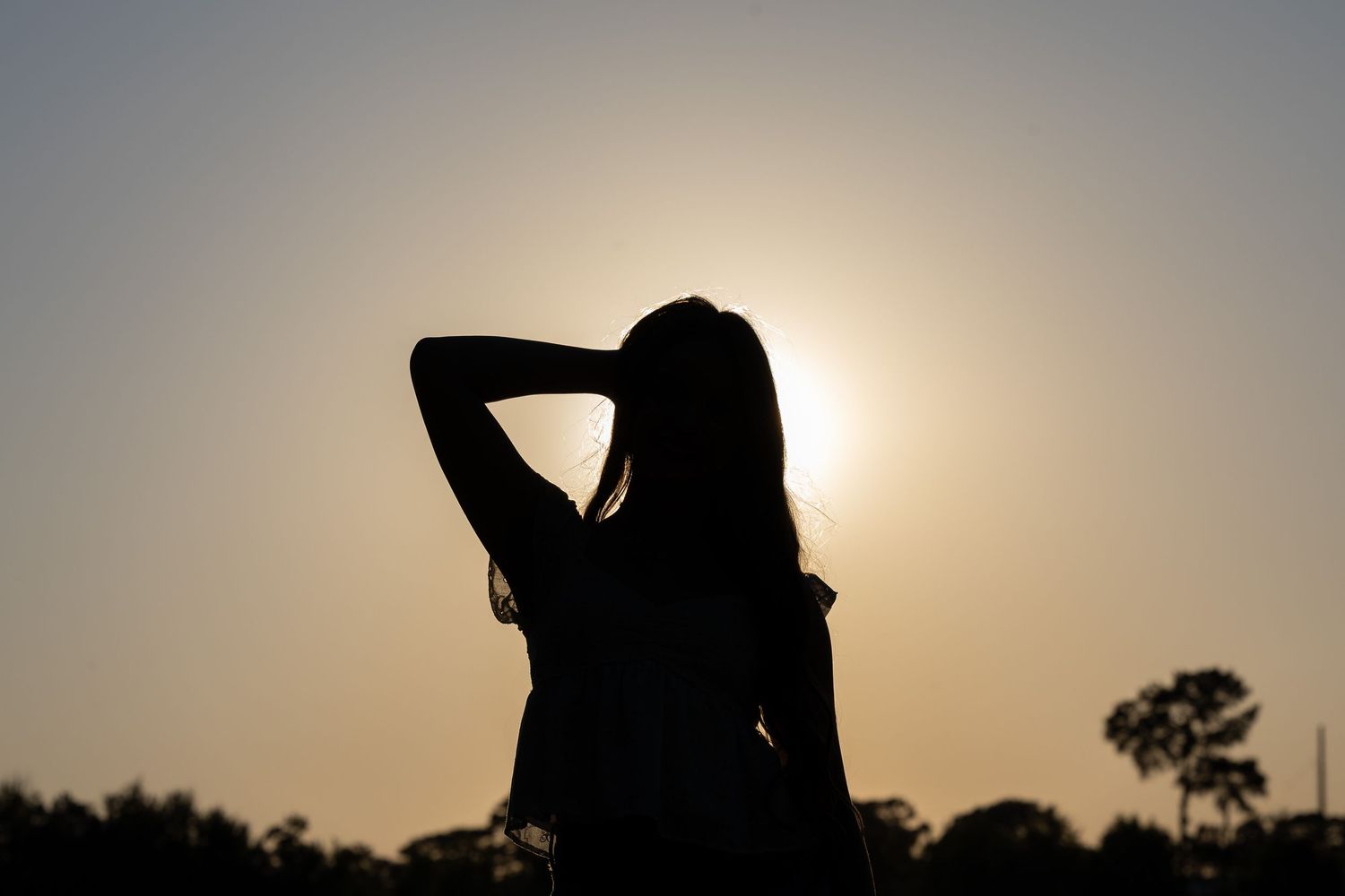 Silhouette of a senior girl against a dramatic sunset background