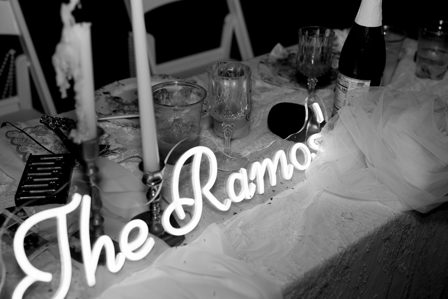 Elegant black and white photo of The Ramos neon sign on a decorated wedding sweetheart table.