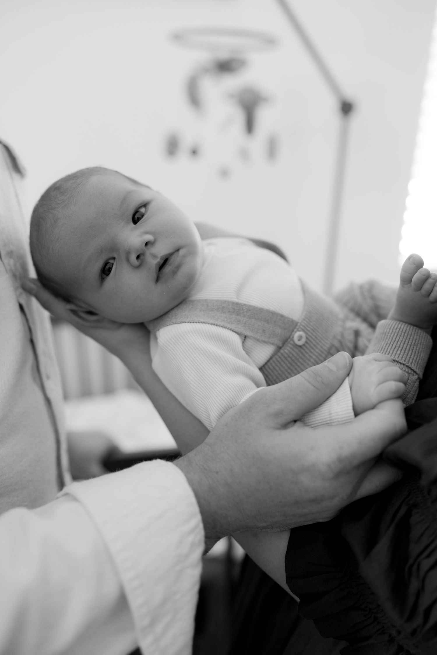 Black and white photo of a newborn baby being held by a doctor during a medical examination.