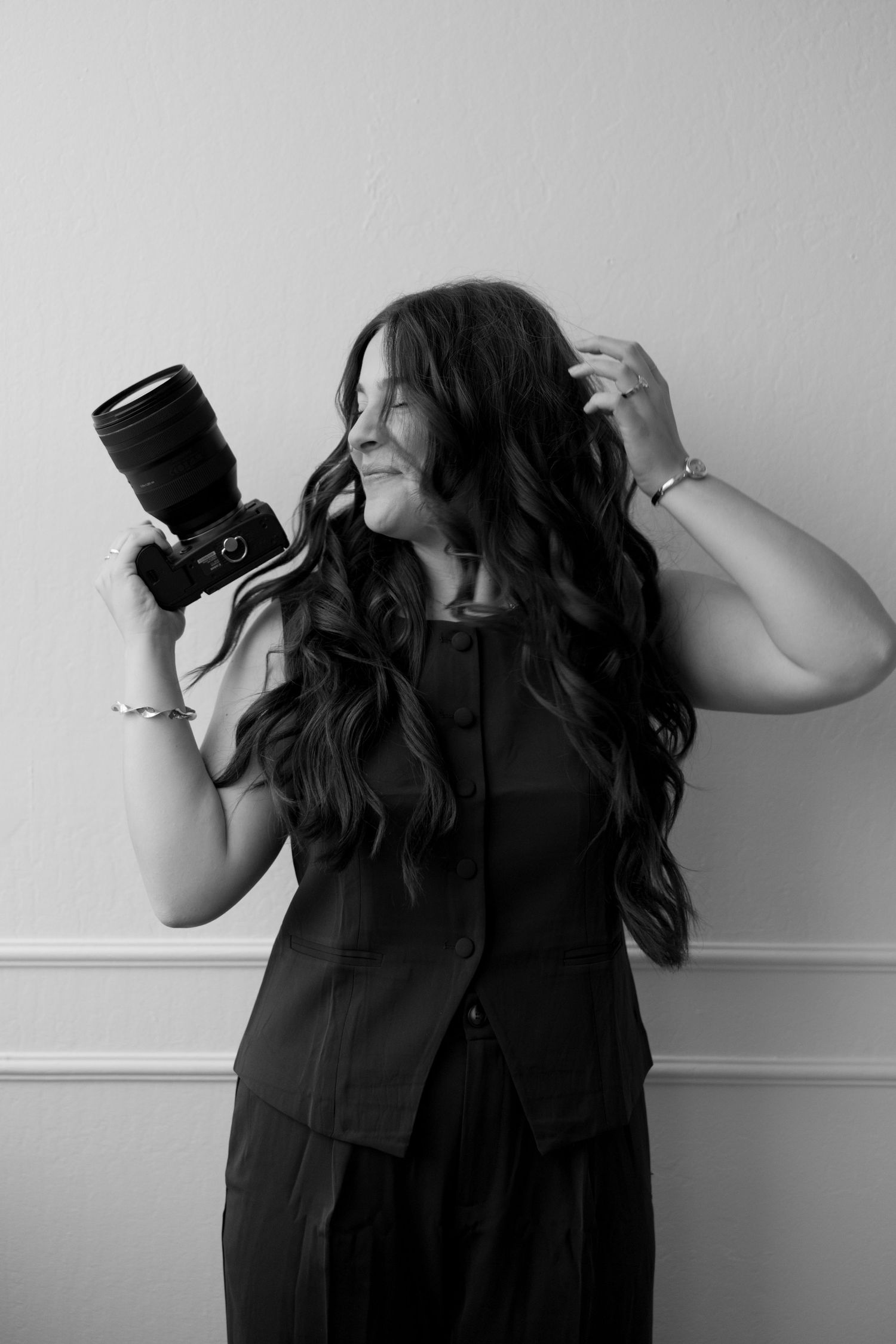 Black and white portrait of a female photographer holding a camera confidently.