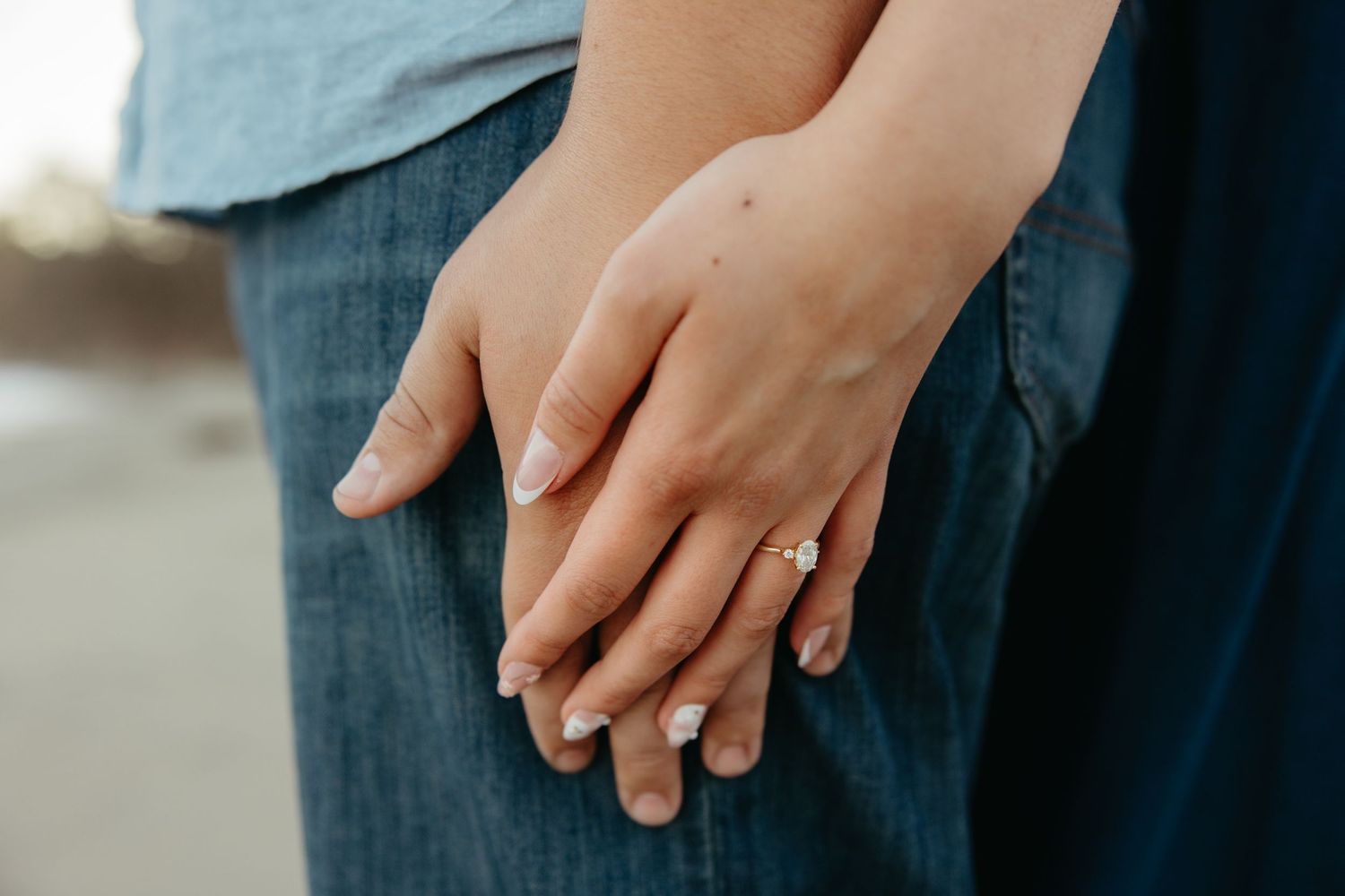 Close-up of couple holding hands showing a beautiful engagement ring on womans finger.