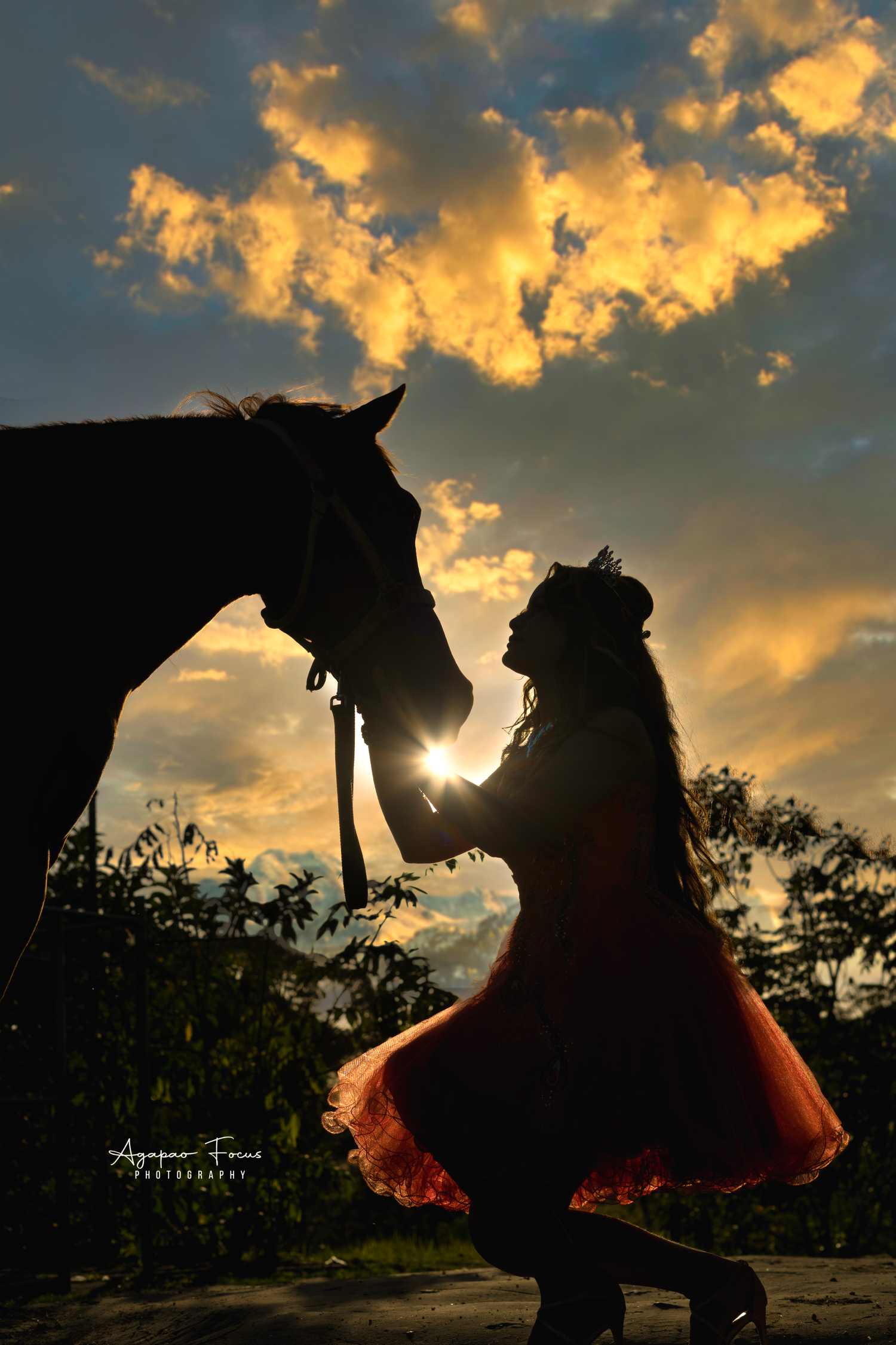 Silhouettes of horses and riders against a dramatic sunset sky with glowing orange clouds.