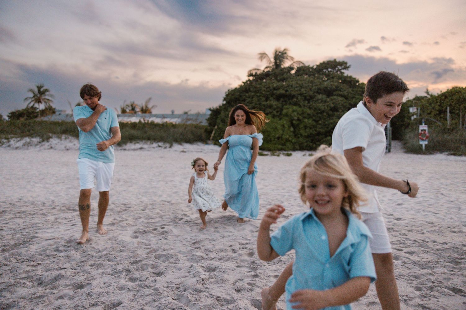 Joyful family playing and running together on a beach at sunset.