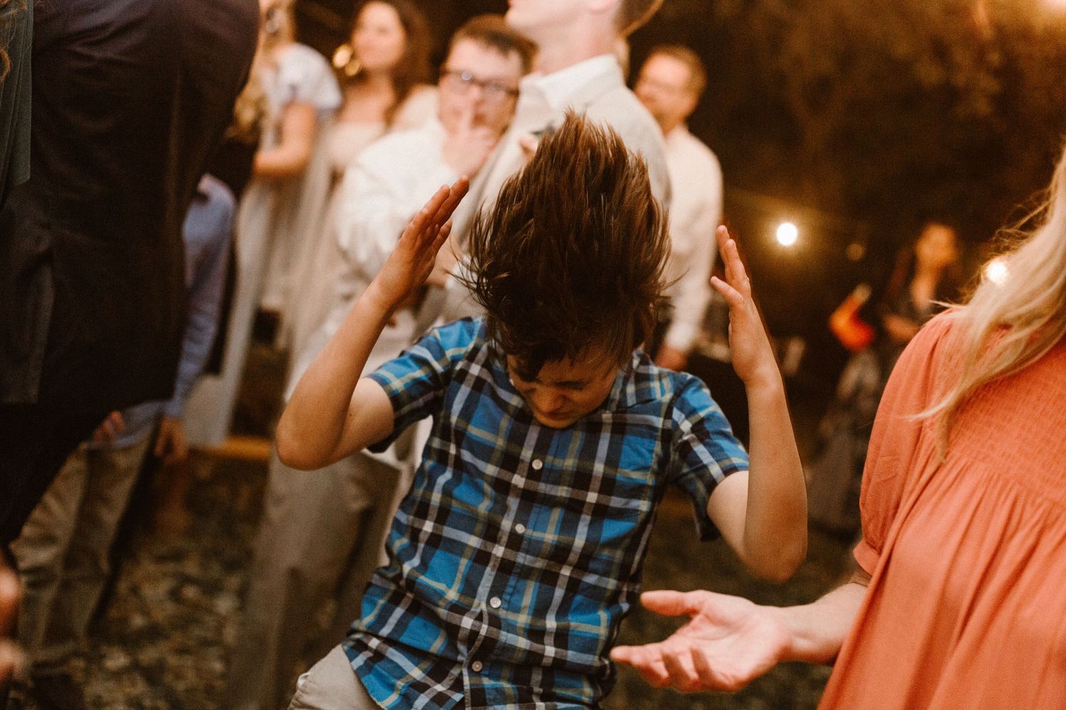 Young boy headbanging energetically on the wedding reception dance floor.