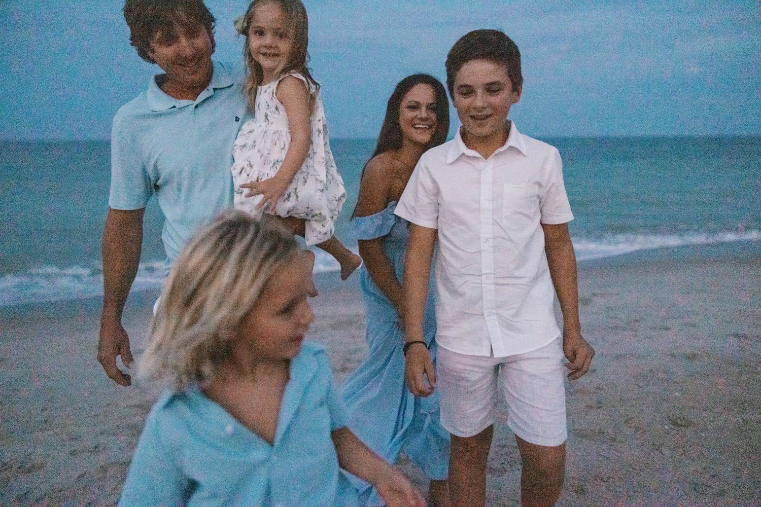 A family enjoying a relaxed evening stroll along a scenic ocean beach.