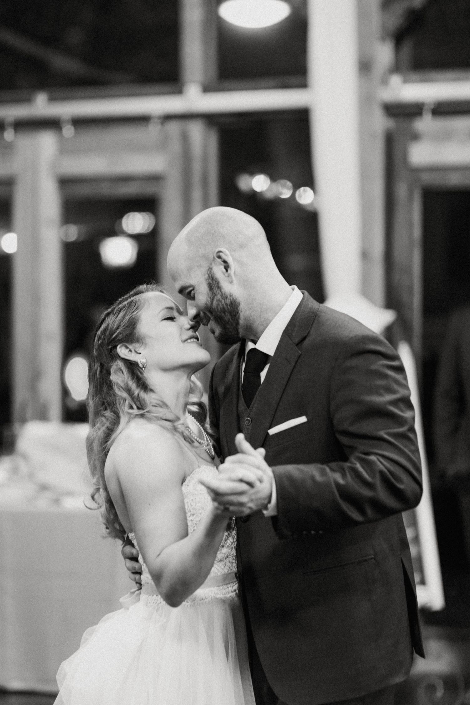 A bride and groom share an intimate first dance in a black and white photo.
