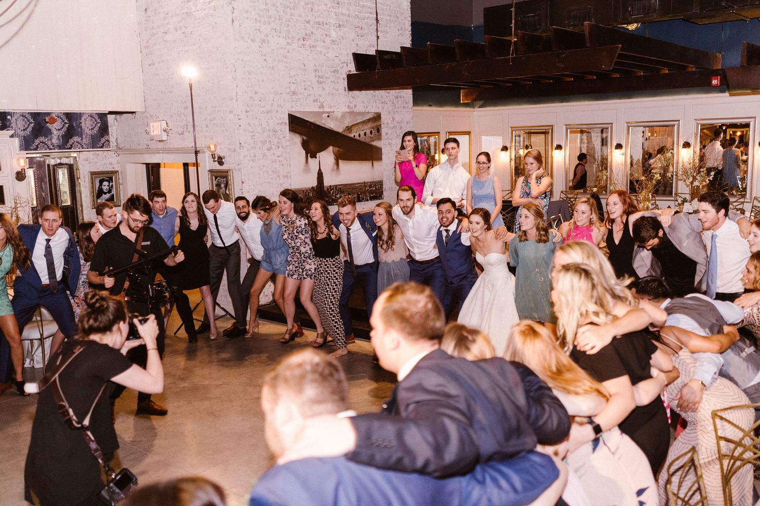 Guests dancing and celebrating at a lively indoor wedding reception venue.