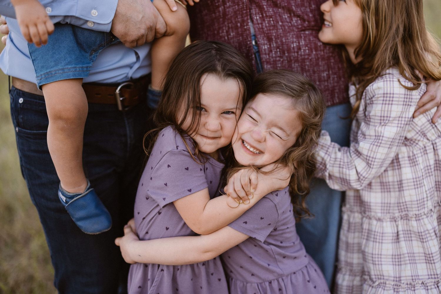 Young siblings sharing a warm group hug during an outdoor family portrait session.