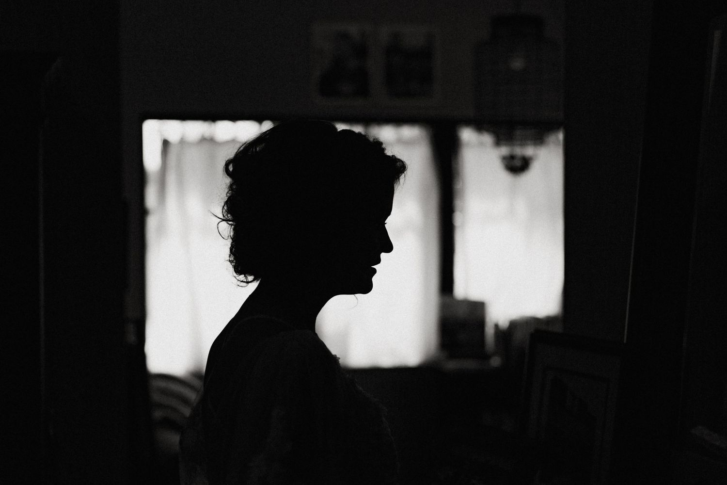 Black and white silhouette portrait of a woman standing near a window indoors.
