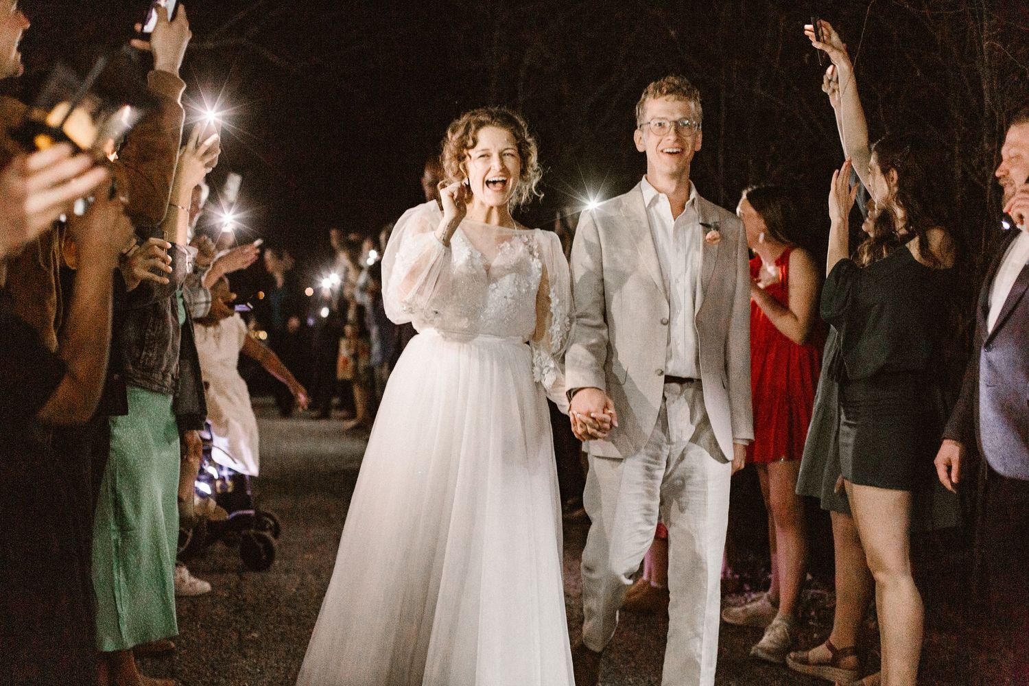 Bride and groom walking through sparkler exit at night wedding reception.