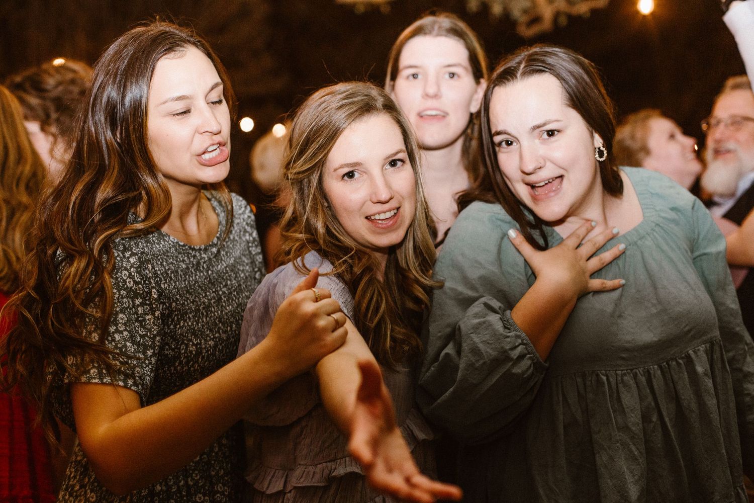 Four young women smiling and posing together at an indoor party event.