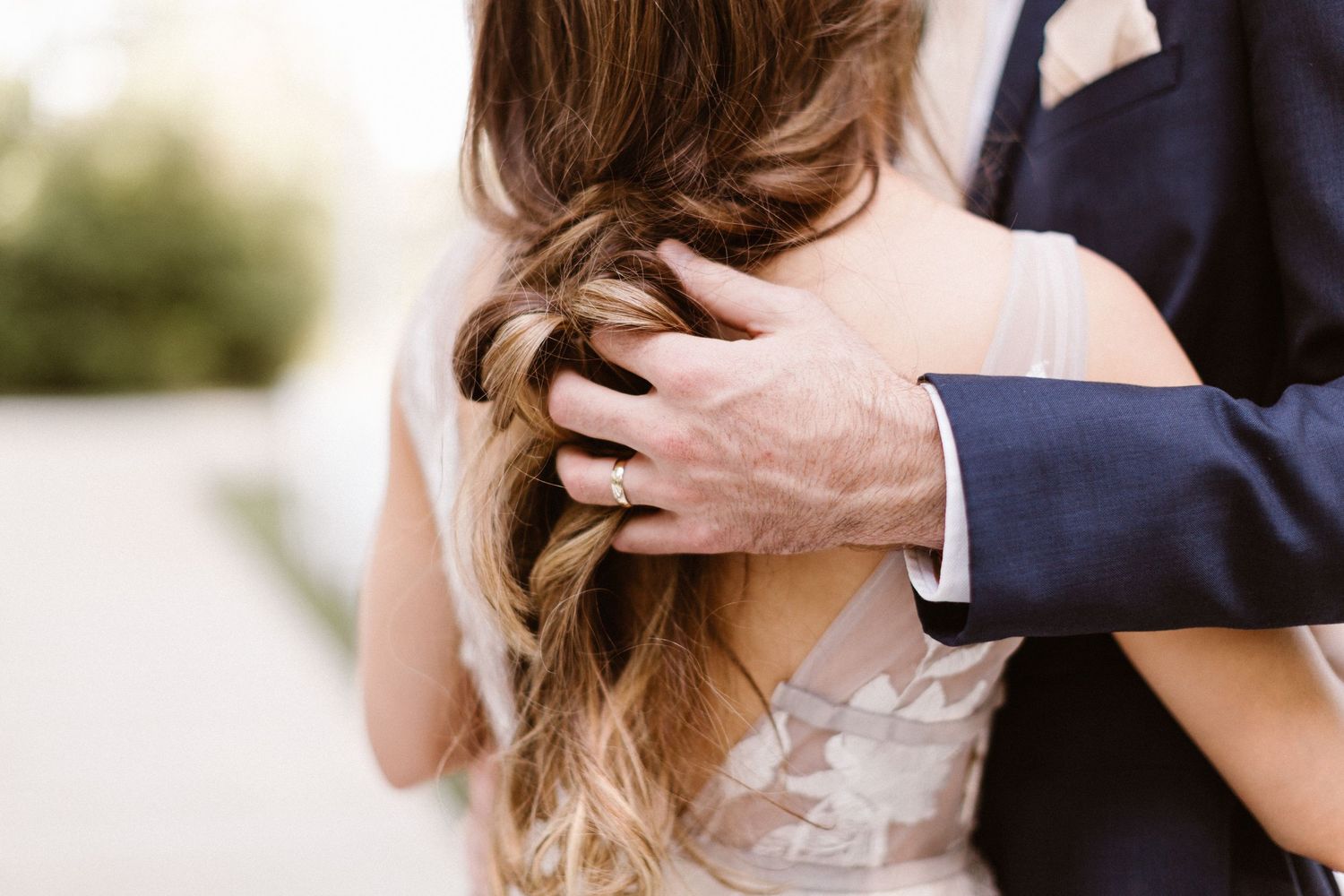 Groom placing hand on brides braided hair in an intimate wedding moment.
