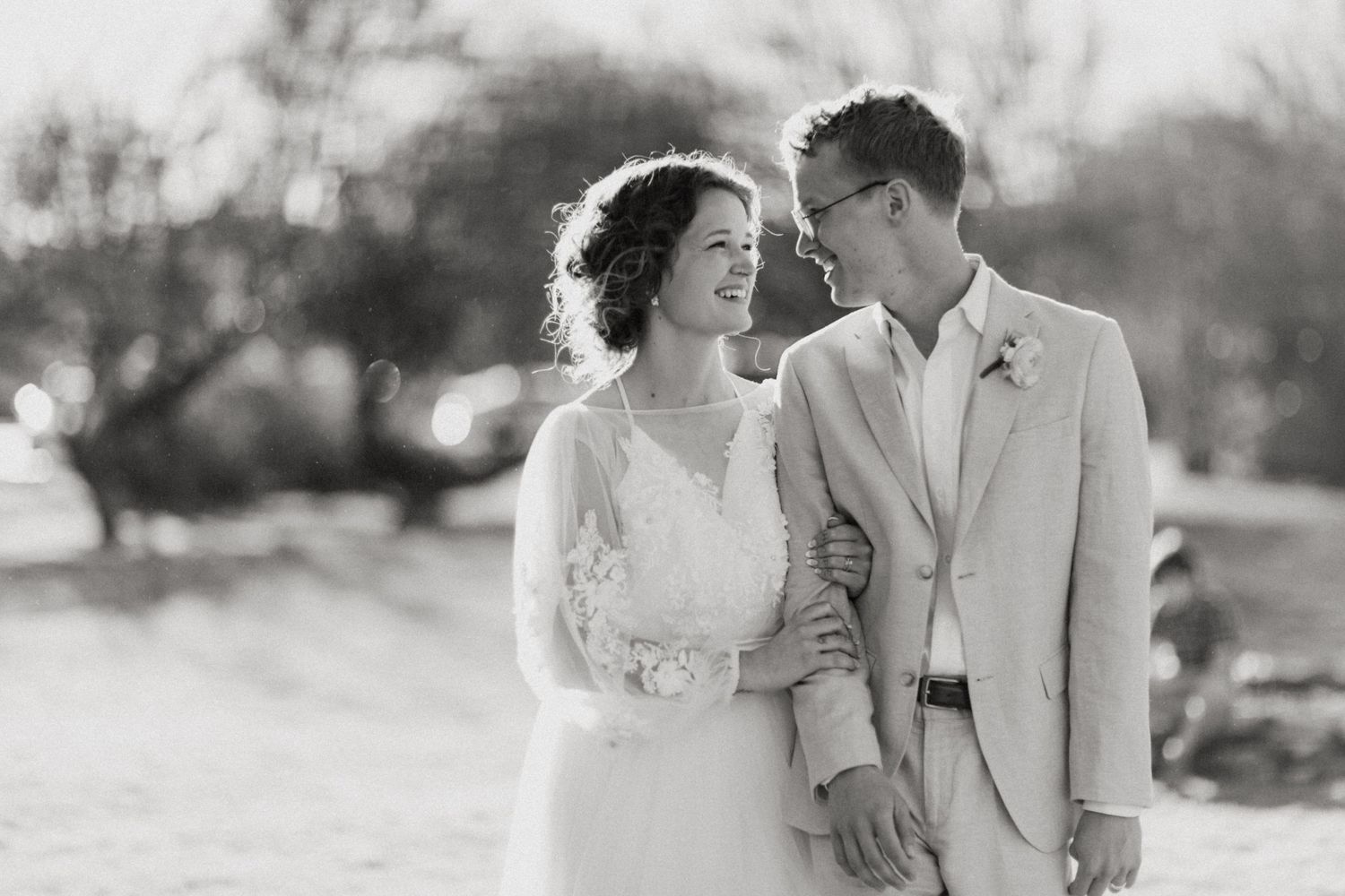 Black and white portrait of smiling bride and groom embracing outdoors on their wedding day.