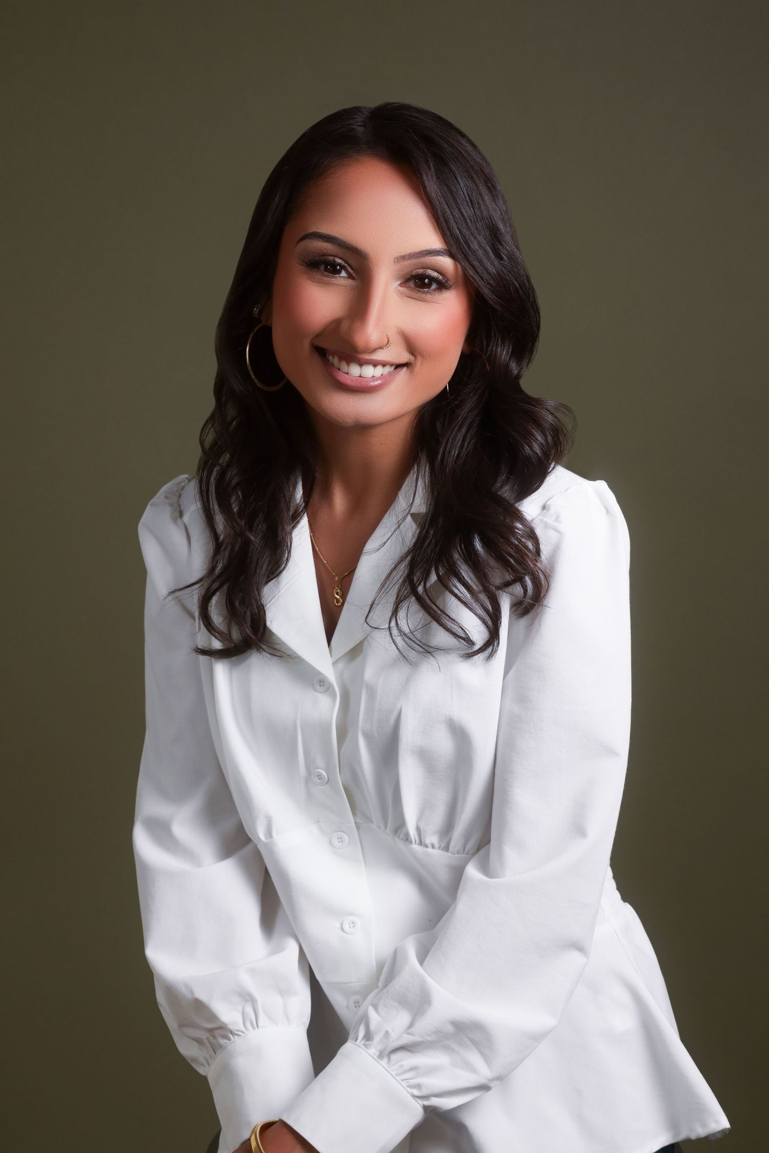 Studio portrait featuring classic white button-down shirt against neutral backdrop.