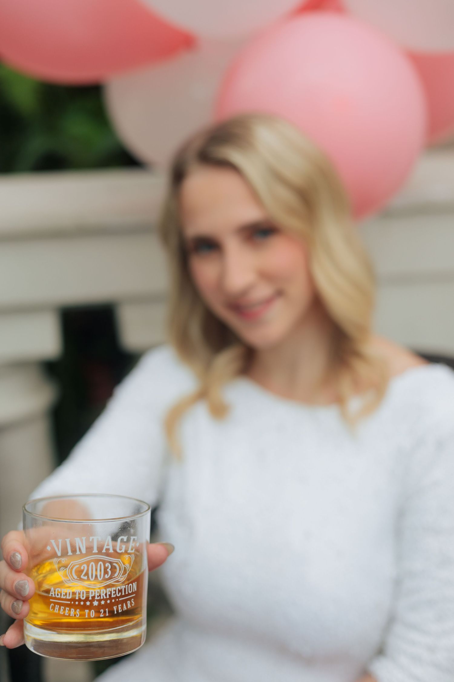 Celebratory scene with champagne glasses and pink balloons in white setting.
