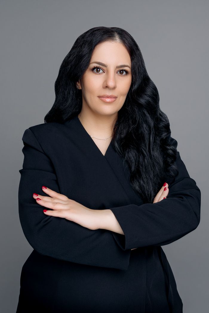 A series of portraits showing a person in a black outfit posing with crossed arms against a gray background.