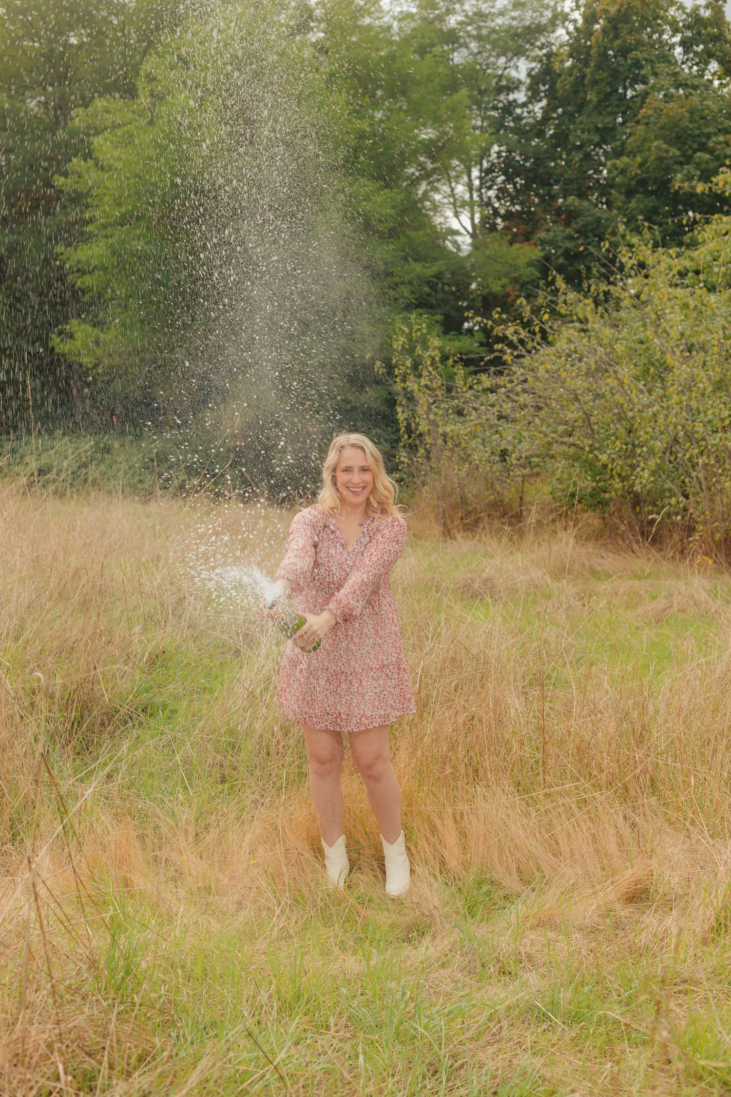 Person in a pink dress dancing and spinning in a field with water splashing around.
