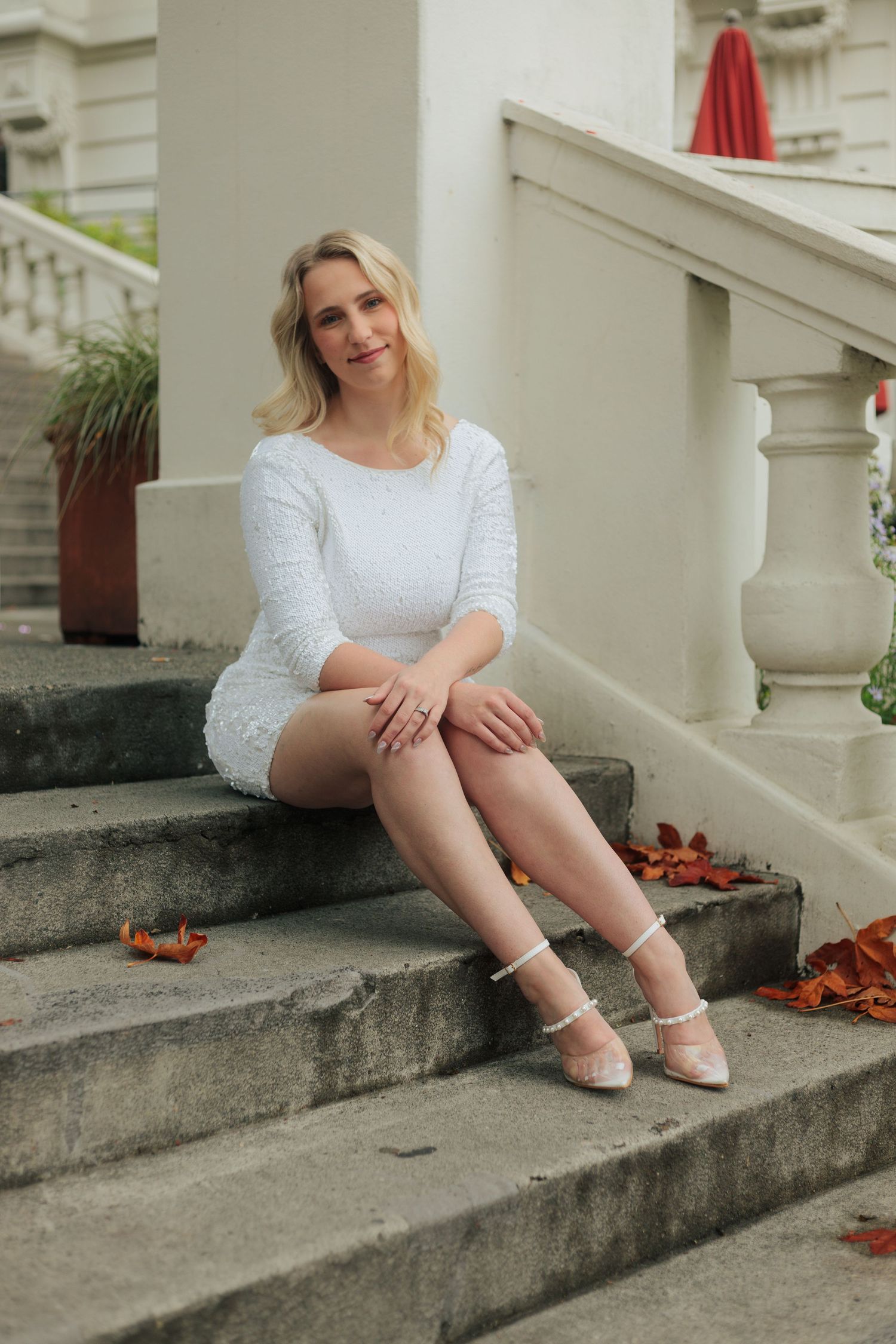 White lace dress and elegant shoes photographed on outdoor stone steps with autumn leaves.