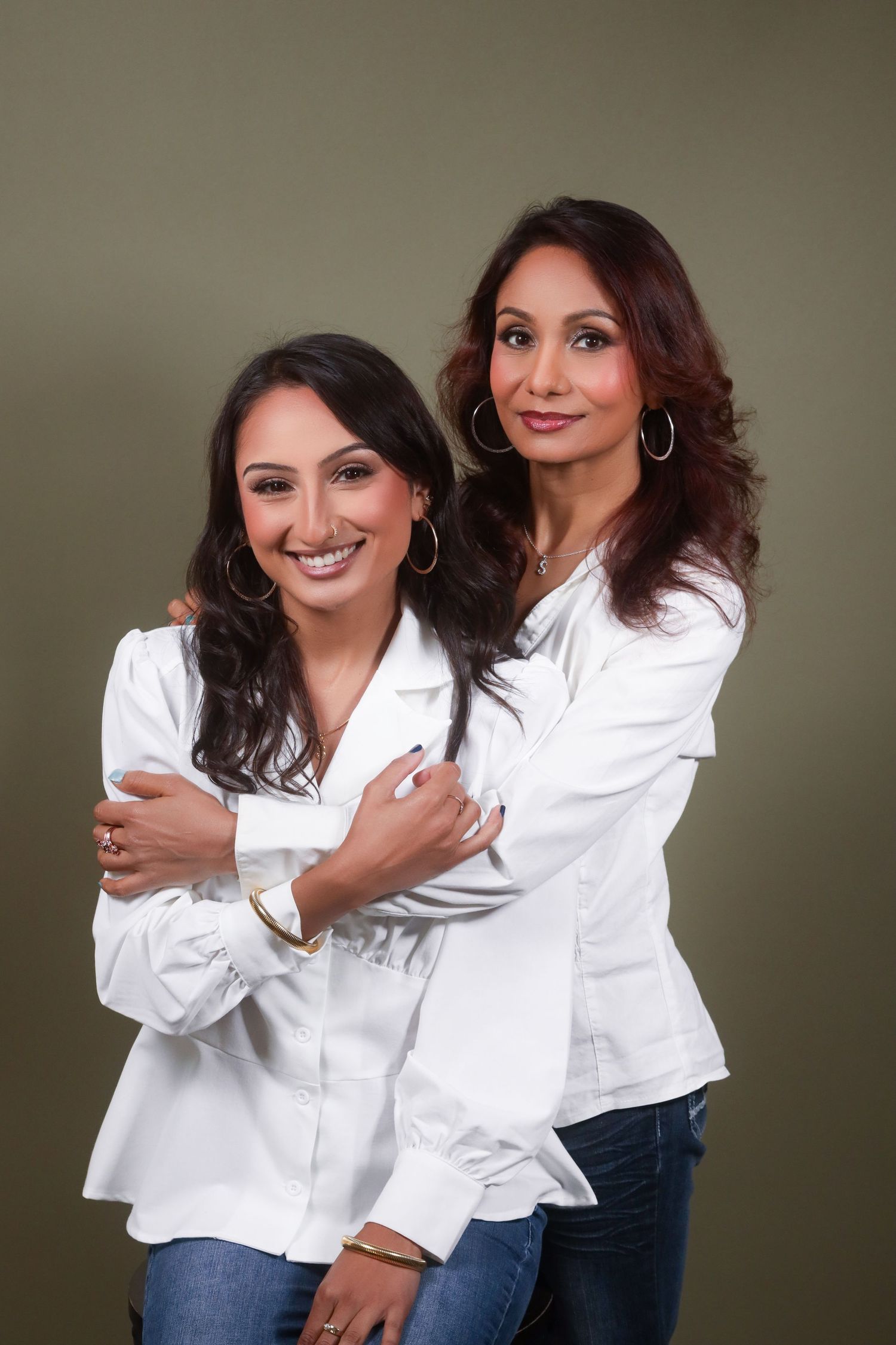 Women wearing matching white shirts embrace and smile during a casual photo session.