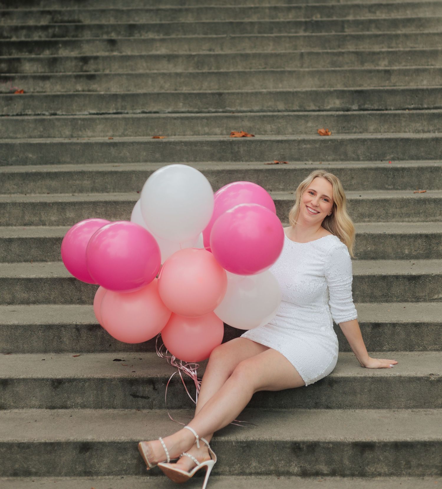 Elegant photoshoot on grand stone staircase with pink and white balloon accents.
