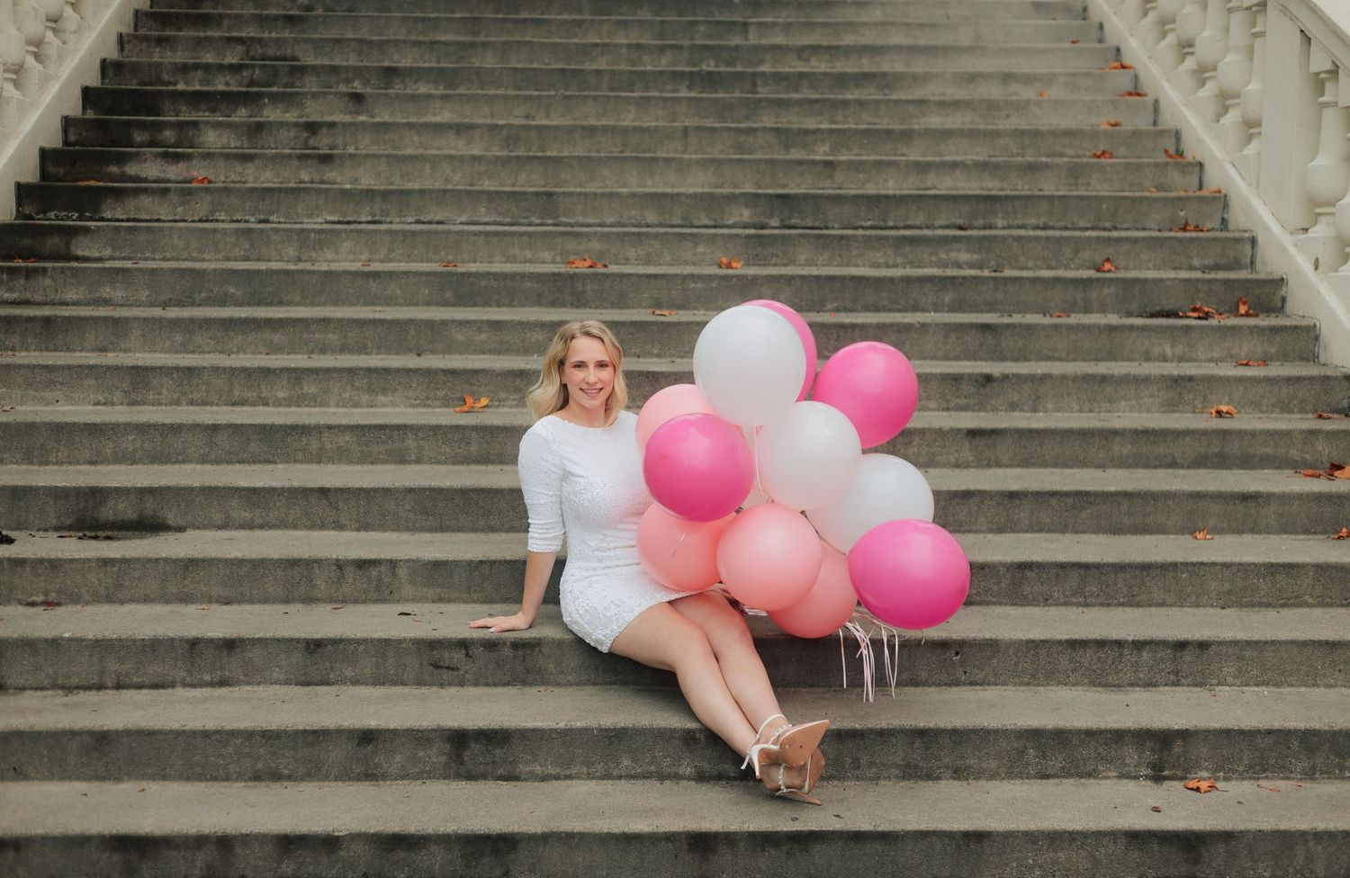 Wide shot of stone staircase decorated with pink and white balloons for portrait session.