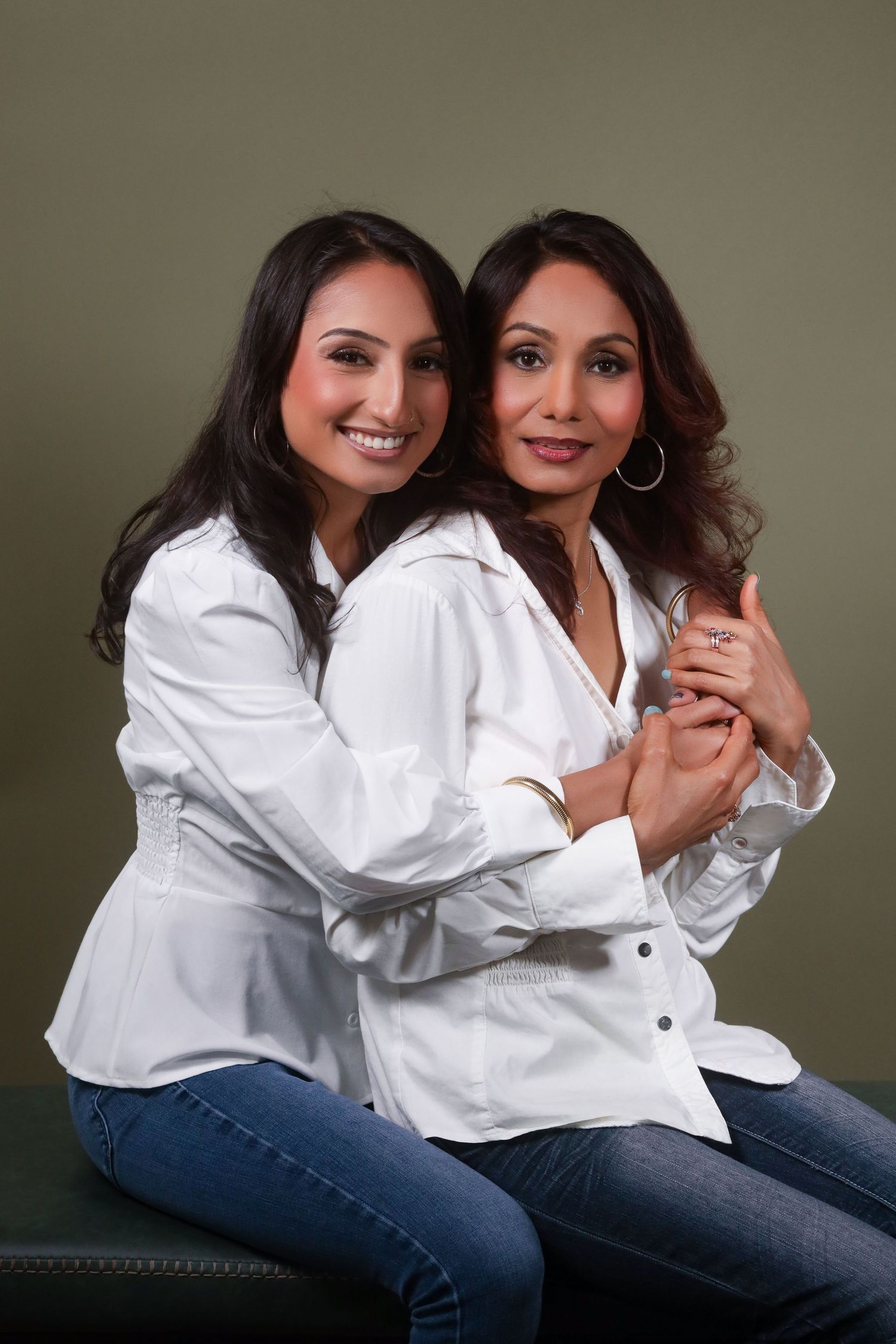Two people in white shirts and jeans share affectionate poses during a studio session.