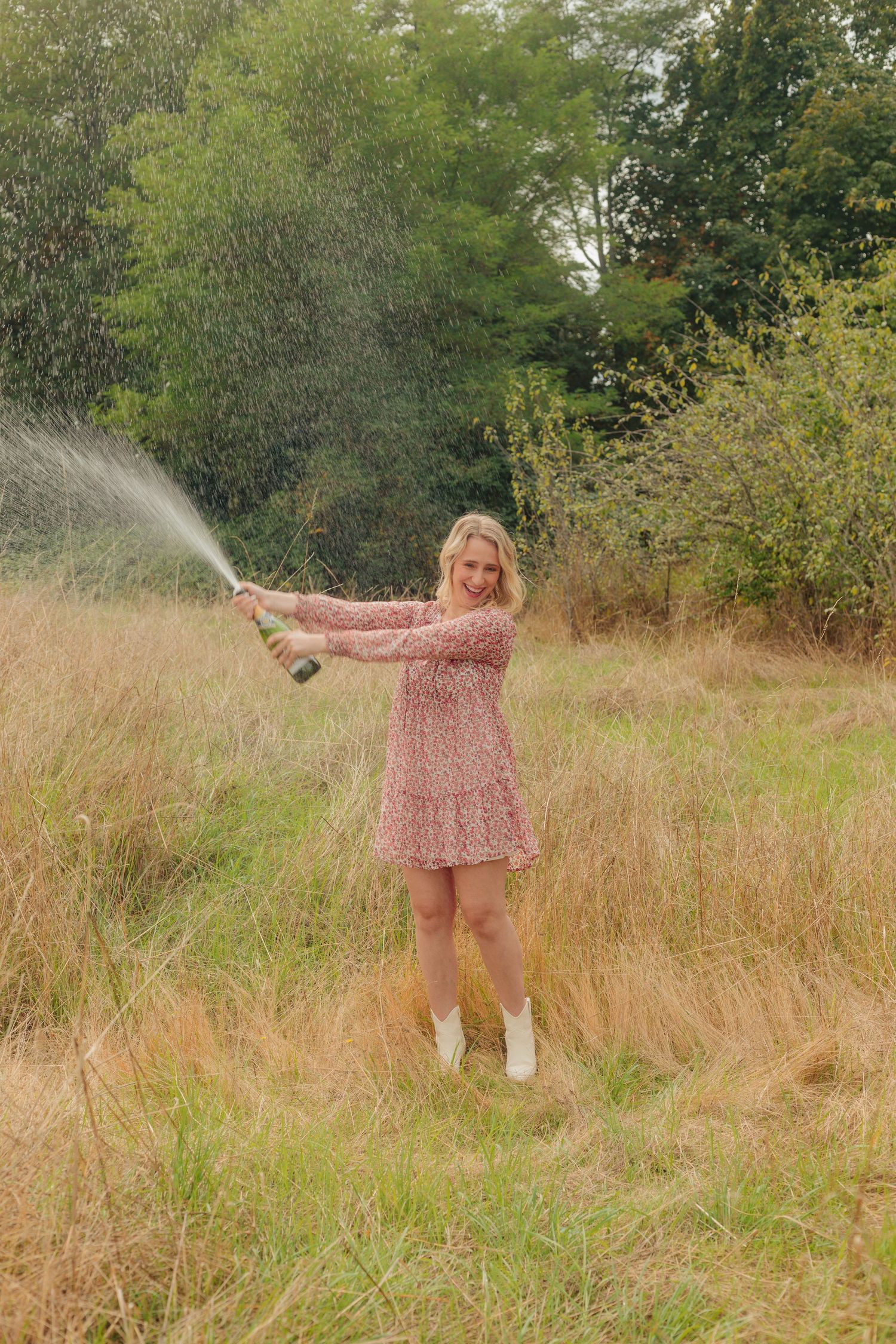 Person in a pink floral dress twirling in a field of tall grass.