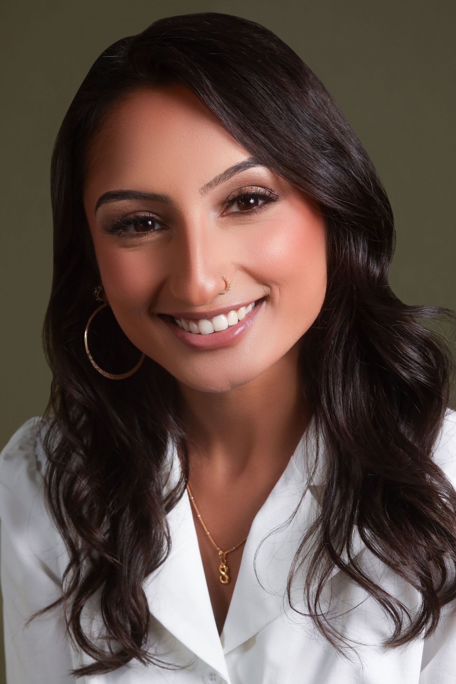 Professional studio portrait with white button-down shirt against dark background.