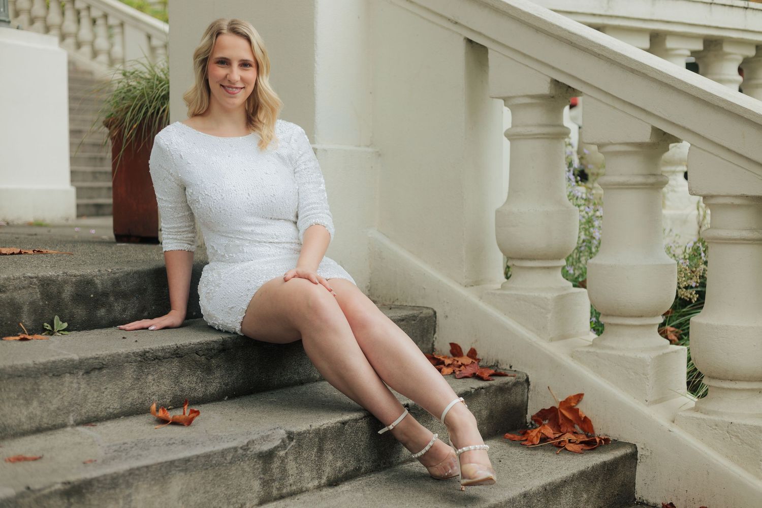 White dress contrasts beautifully against weathered stone steps in outdoor portrait.