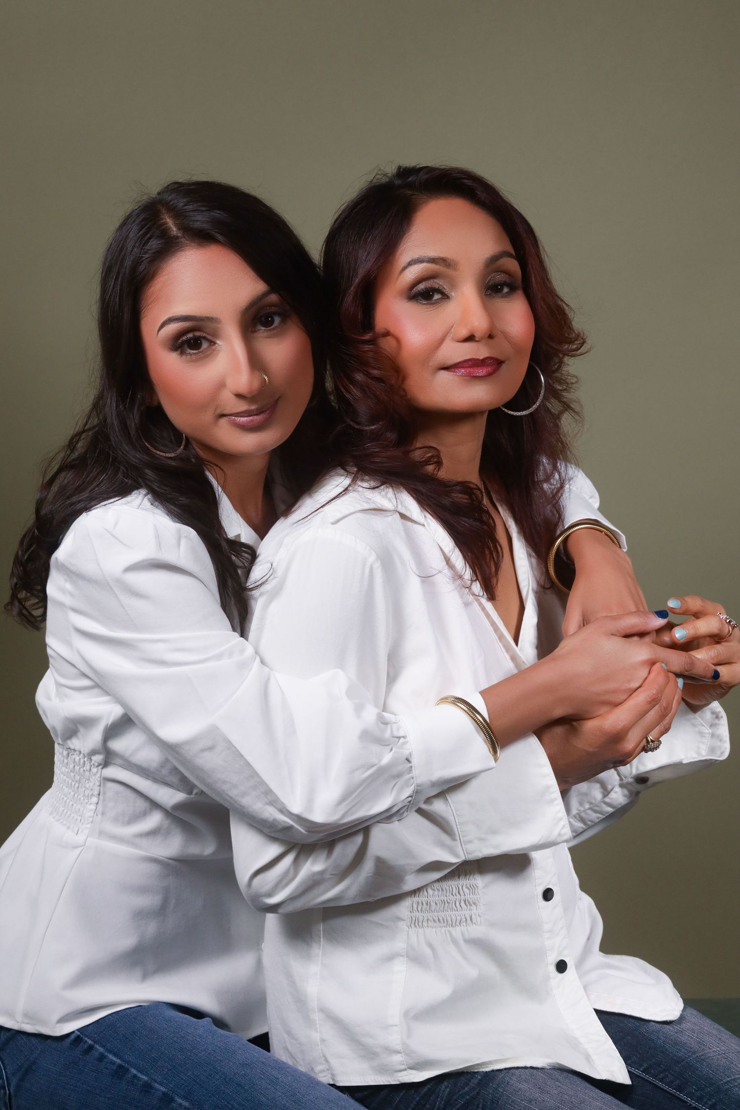 Friends in coordinated white shirts and jeans share candid moments during a photoshoot.