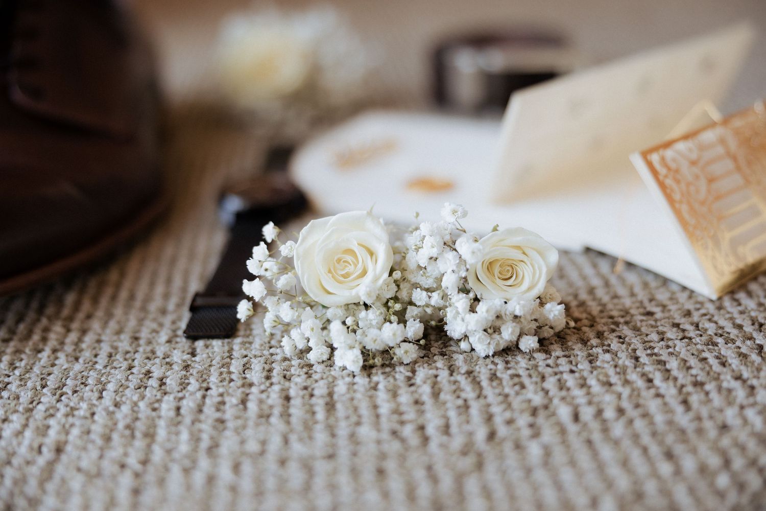Boquet de rosas brancas com flores de mosquitinho sobre uma superfície texturizada, perfeitas para uma flor de lapela de casamento.
