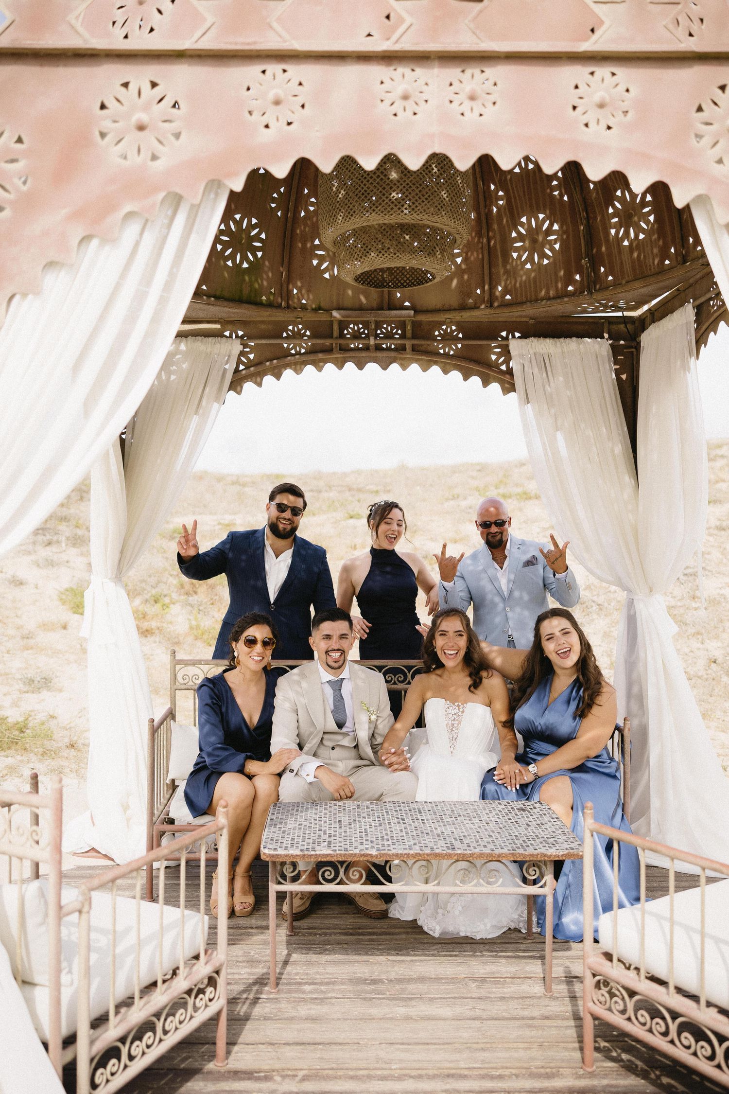O casal de noivos posa com os convidados num cenário desértico. Casamento no Set Lounge Azurara