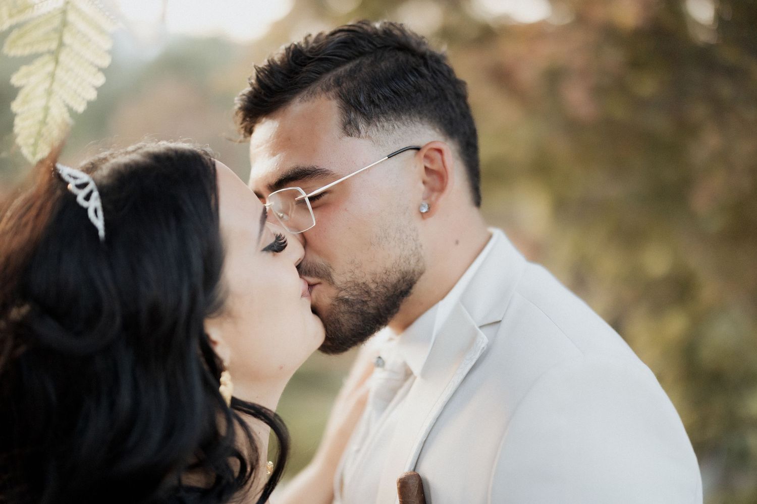 Uma noiva usando tiara e um noivo de fatobranco trocando um beijo romântico ao ar livre no dia do casamento na Quinta do Cruzeiro.